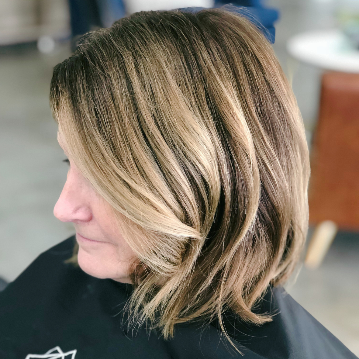 Side view of a woman with shoulder-length, layered blonde hair with darker lowlights.