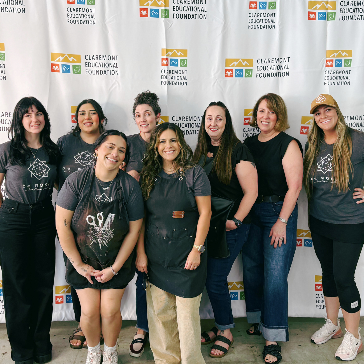 Group of women standing in front of a Claremont Educational Foundation banner, smiling for a photo.