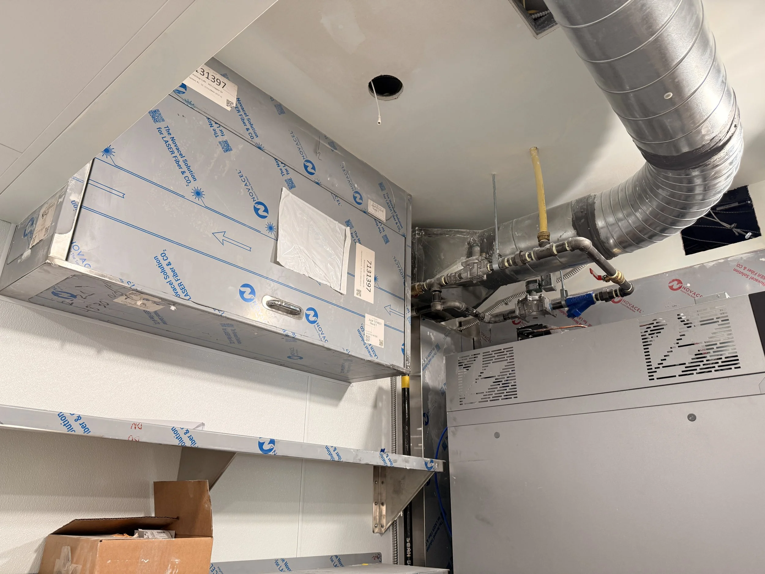 HVAC system installation with metal ductwork, control panel, and insulation in progress at a construction site.