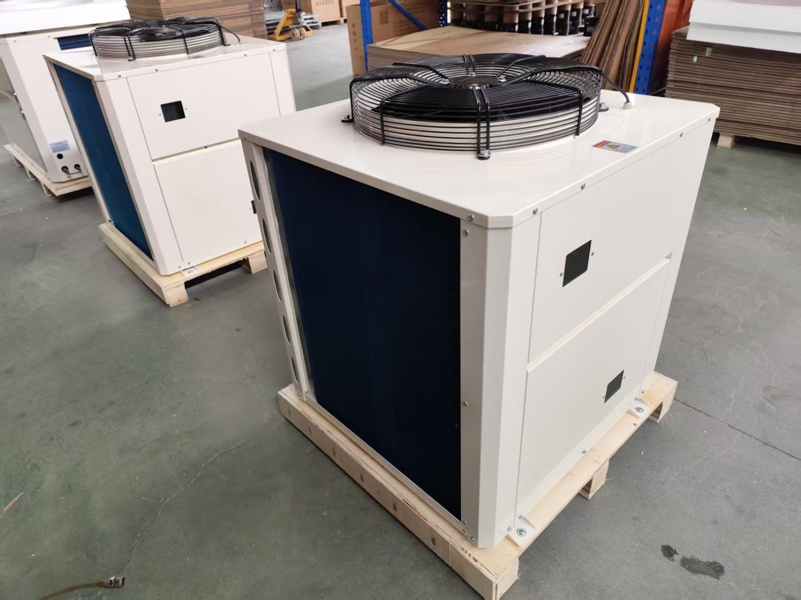 Two industrial HVAC units on wooden pallets in a warehouse