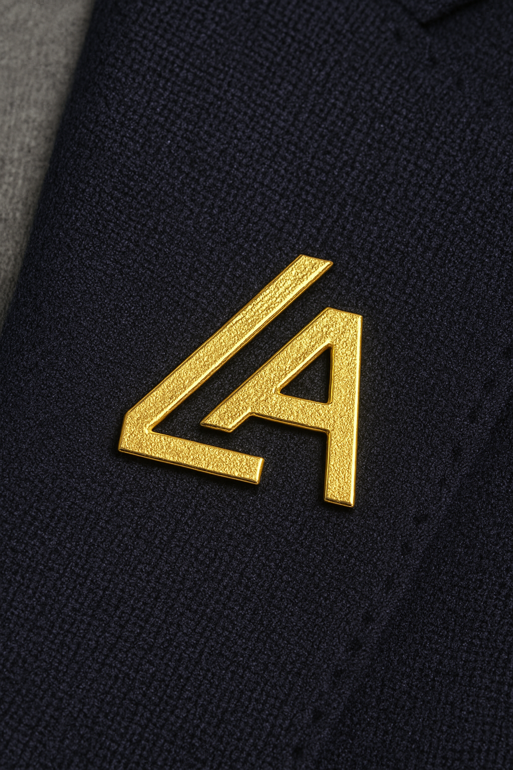 Close-up of a gold LA badge on a dark navy fabric surface.