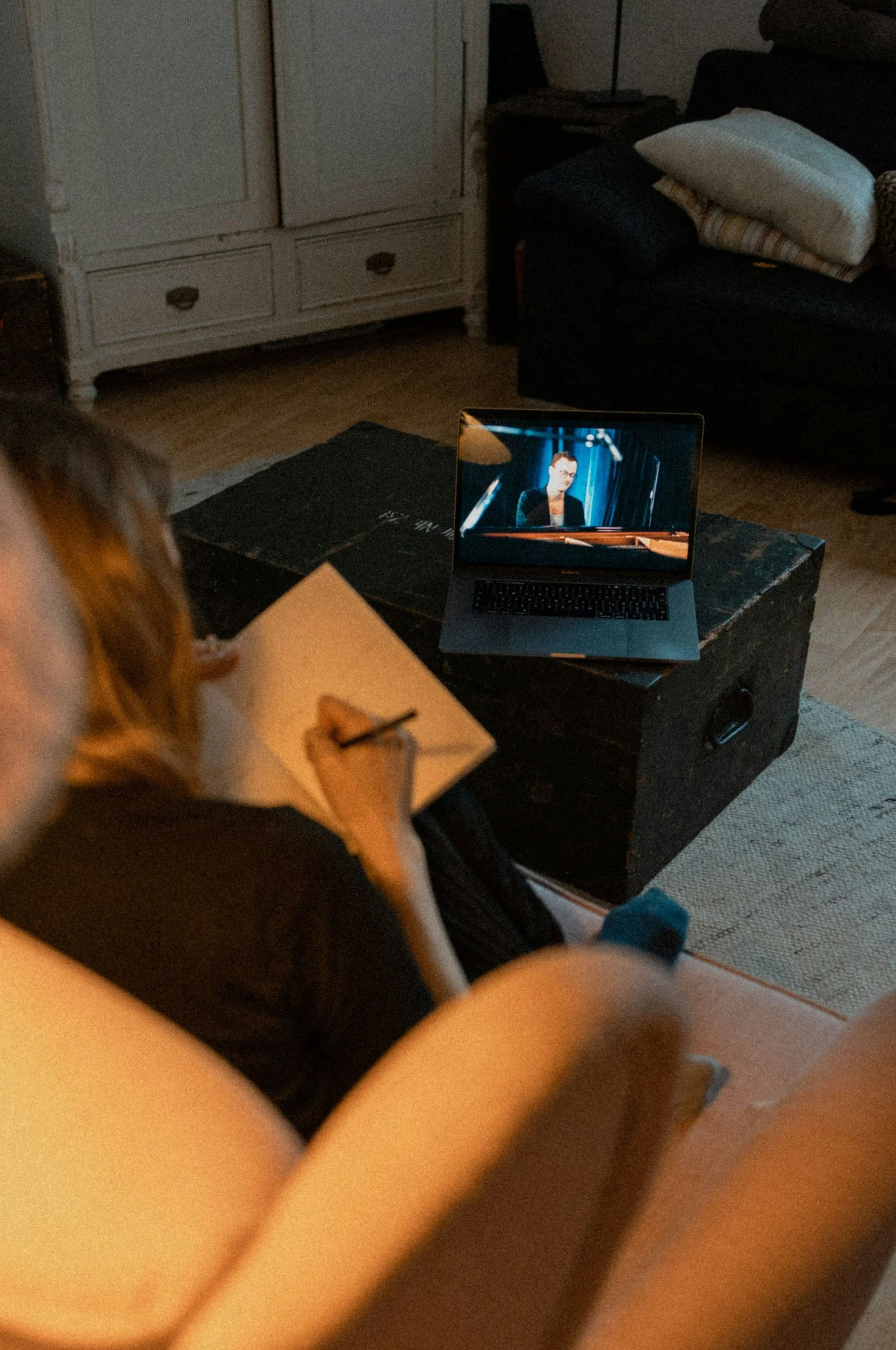 Woman taking notes while watching an online course video