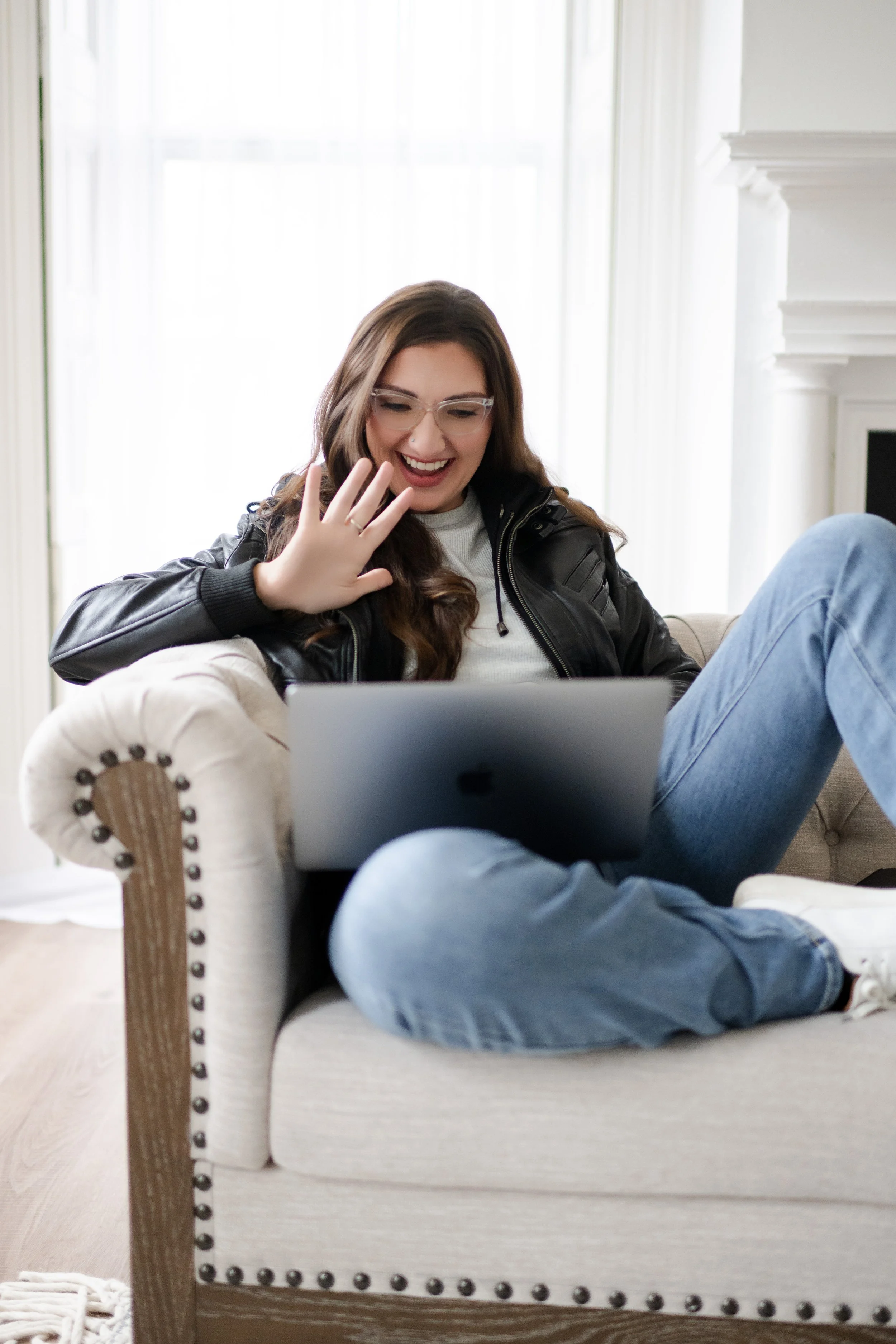Liz August, founder of Simplify Simplify, laughing and waving on a video call with laptop
