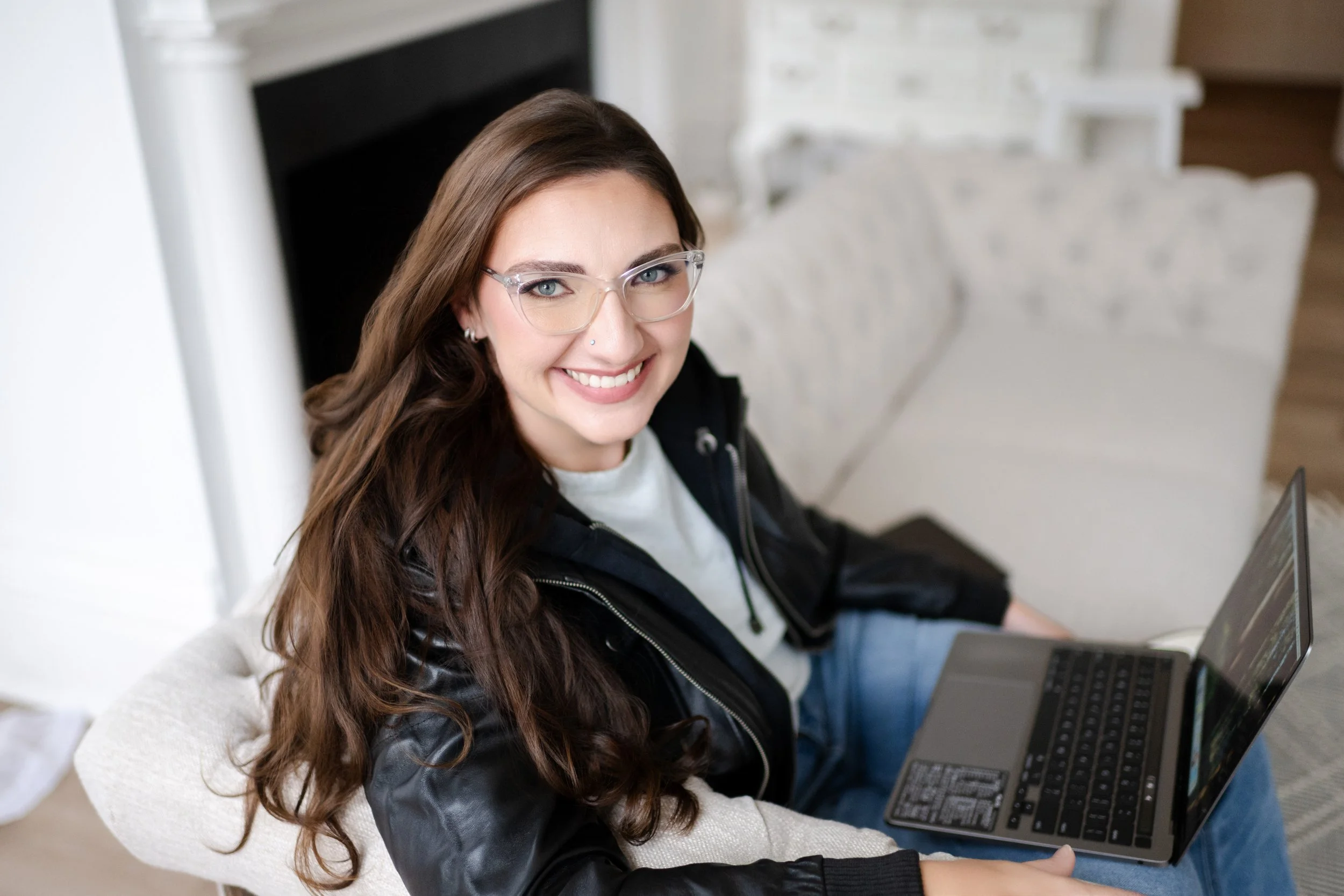 Liz August, business strategist and founder of Simplify Simplify, smiling while working on a laptop.