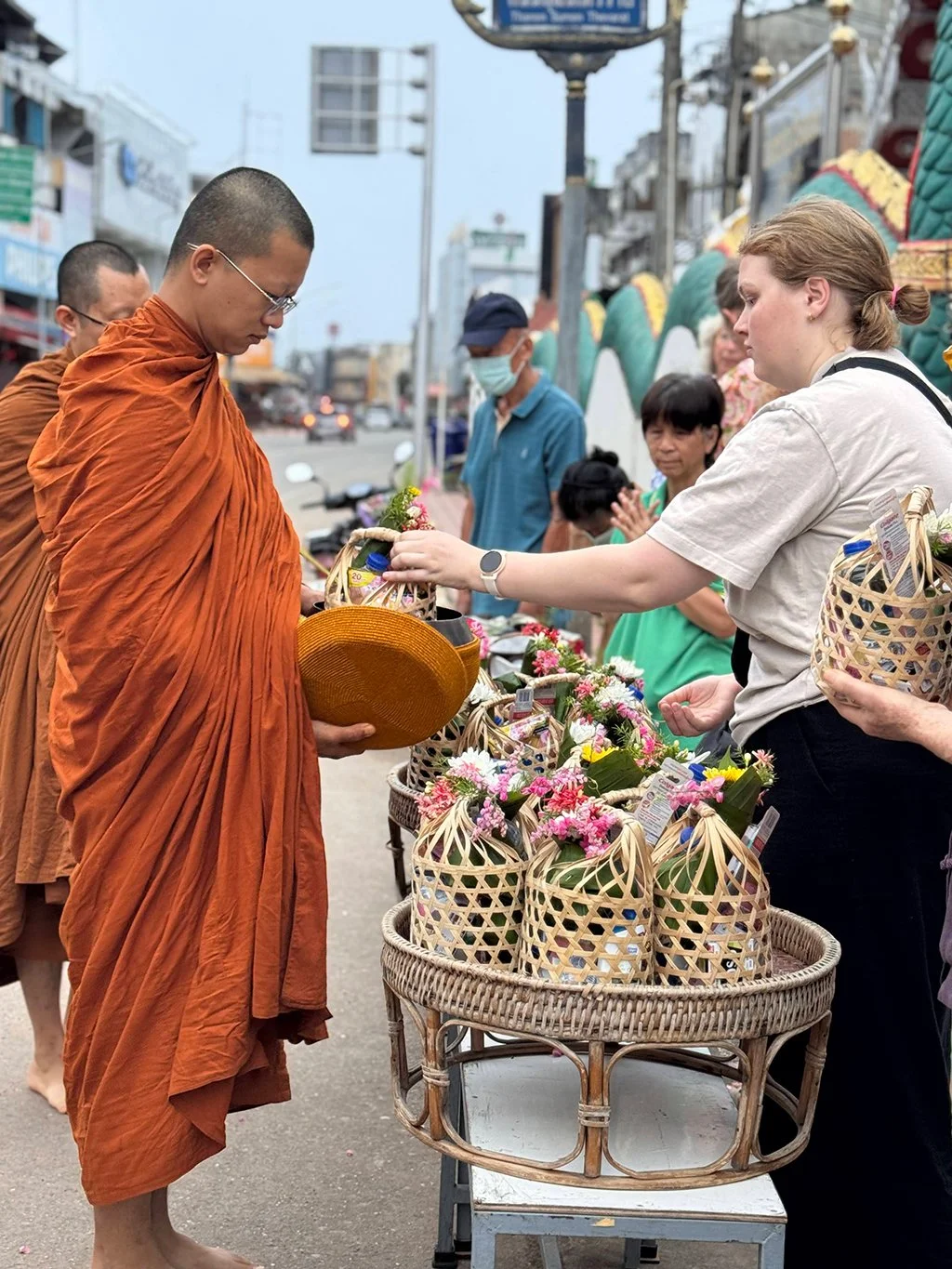 Buddhist monks receiving woven baskets decorated with flowers