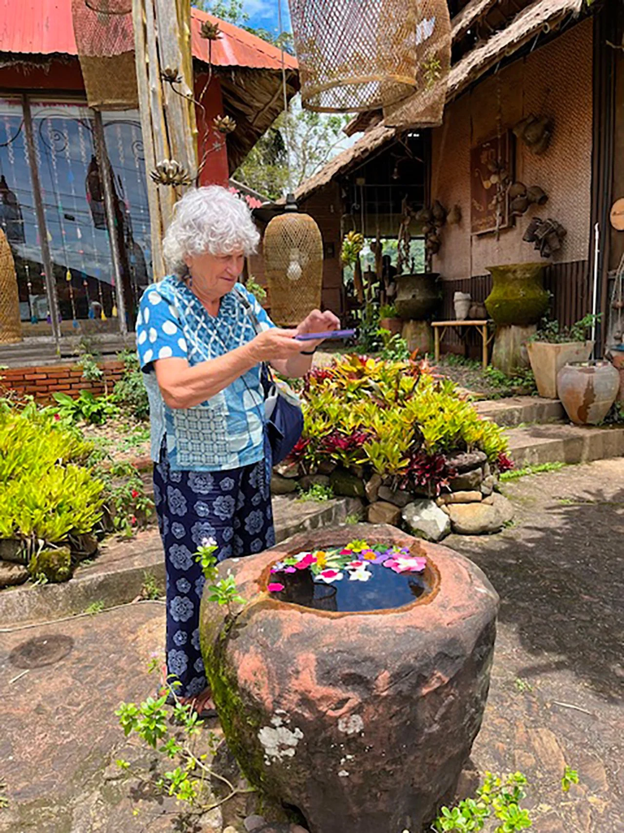 Gillian standing behind a rock filled with water and flowers