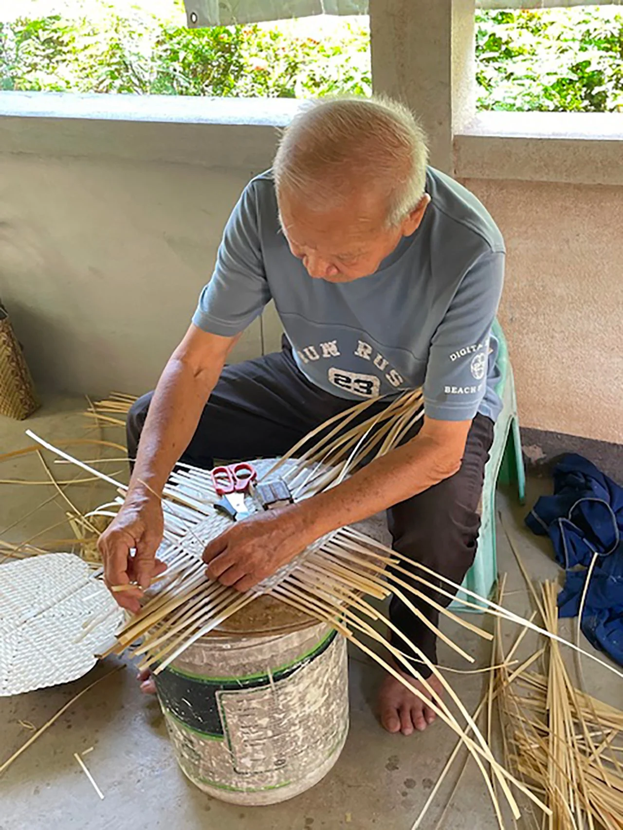 Man weaving bamboo fan