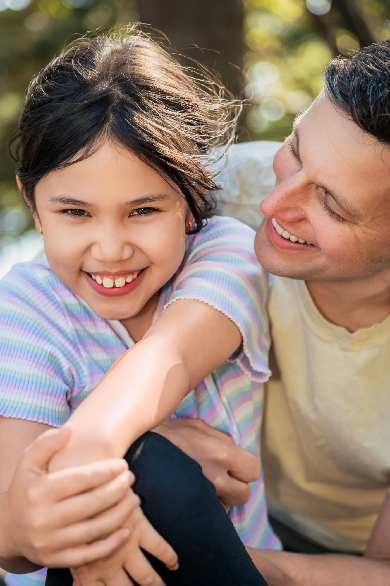 A father and daughter sharing a joyful moment during a relaxed outdoor family photoshoot by Southern Exposure Photography.