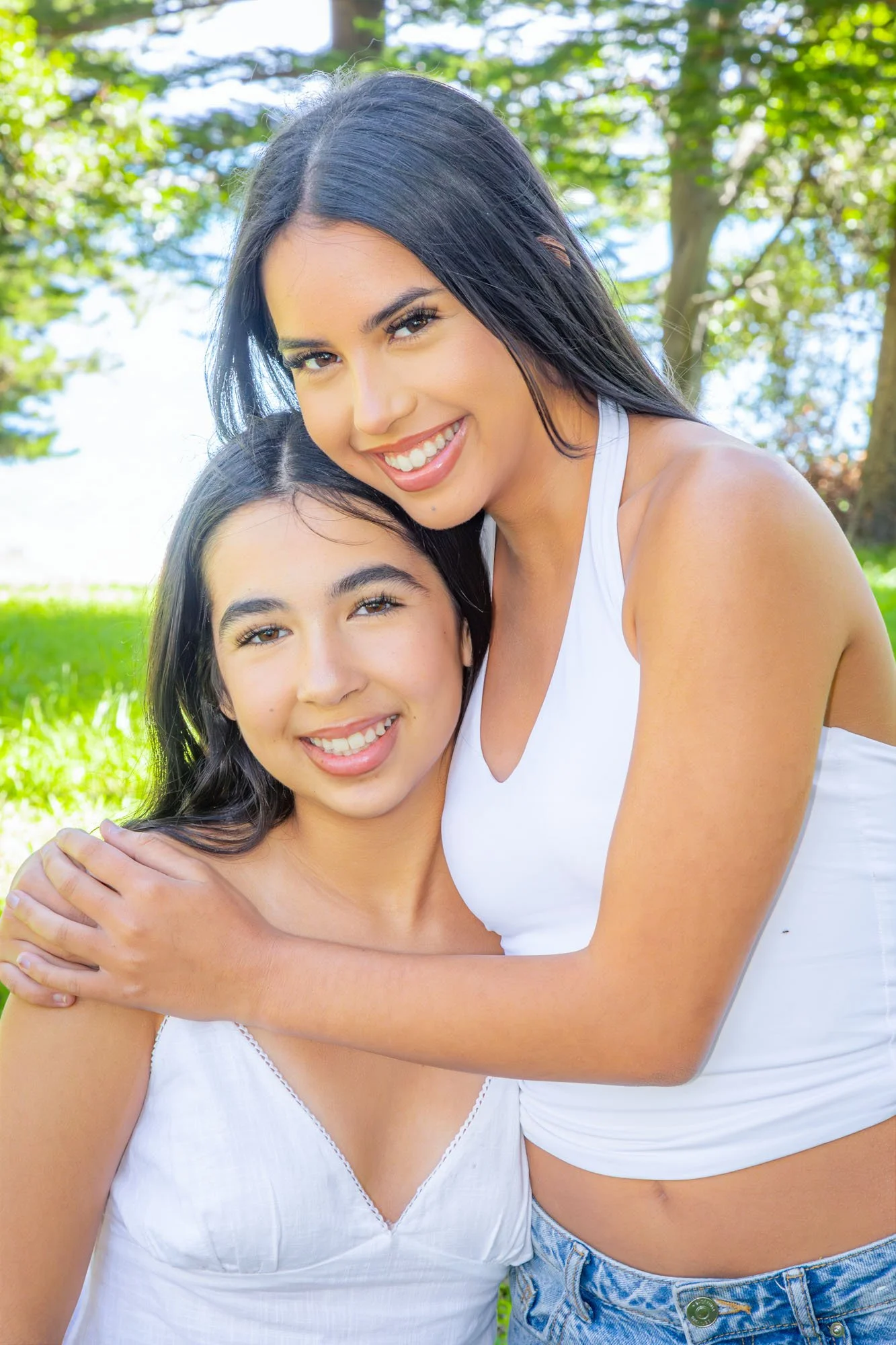 A candid portrait of two sisters sharing a warm moment during an outdoor family photoshoot by Southern Exposure Photography.