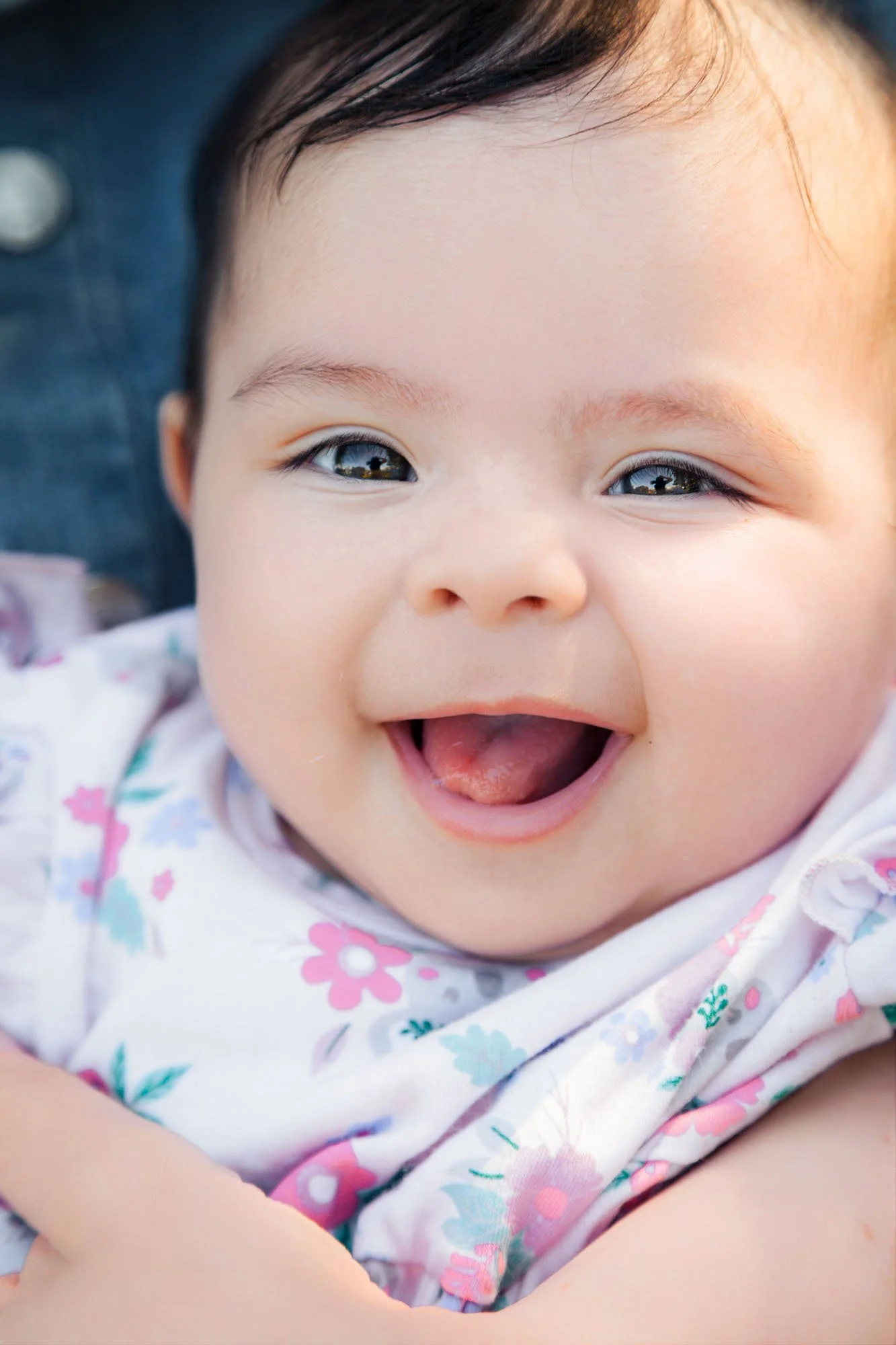 A close-up portrait of a smiling baby during a relaxed outdoor family photoshoot by Southern Exposure Photography.