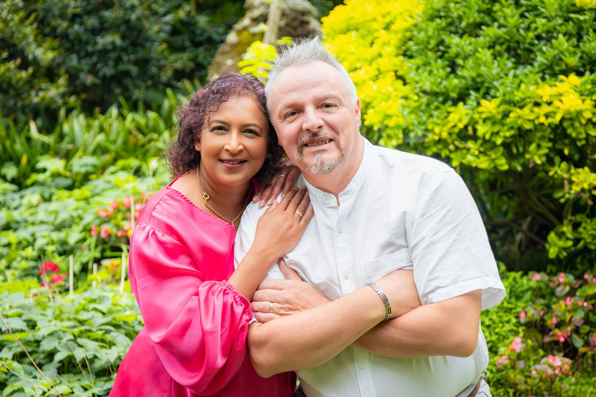 A couple embracing in a lush garden during a relaxed outdoor family photoshoot by Southern Exposure Photography.