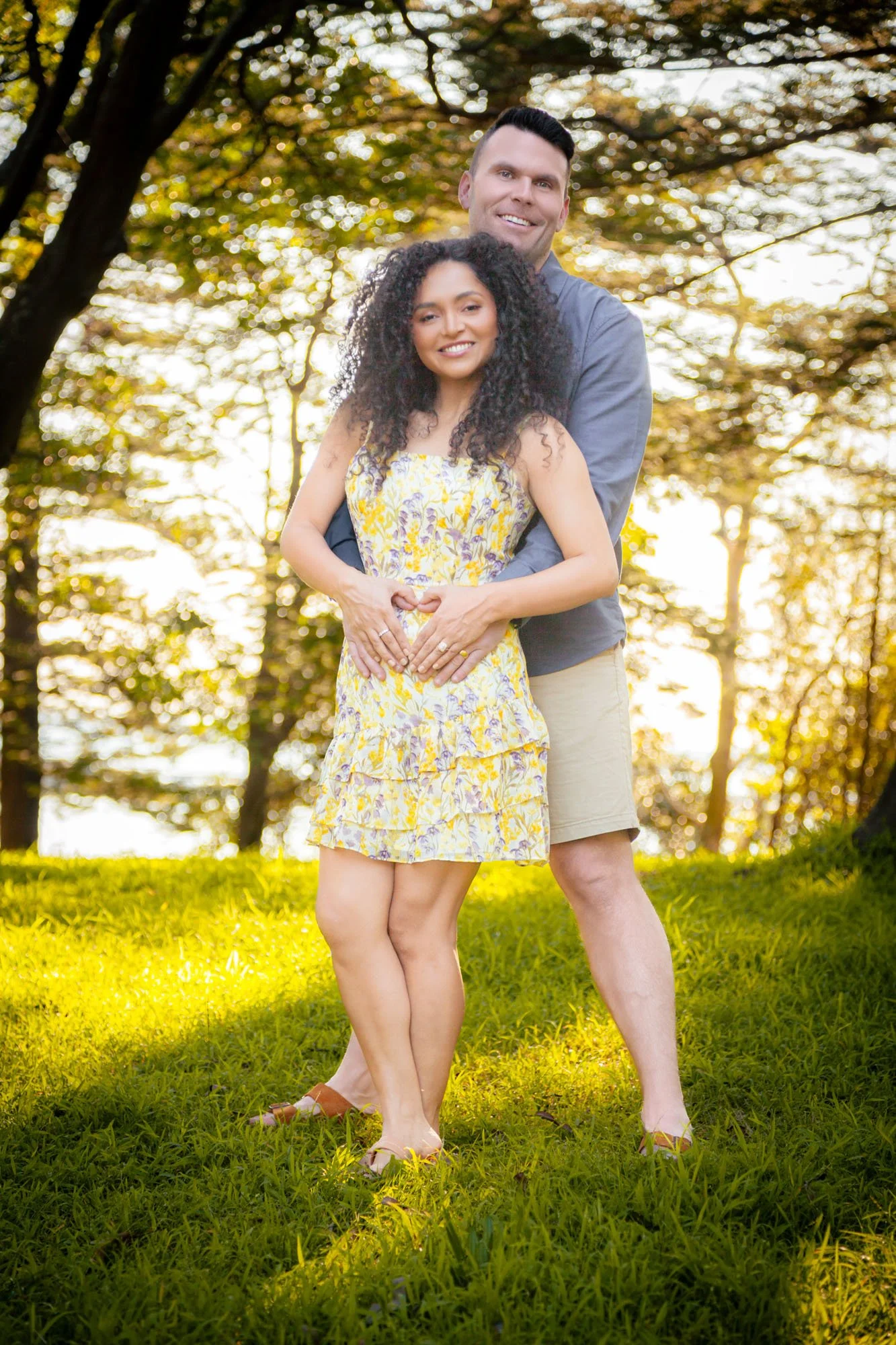 A pregnant woman and her partner sharing a warm embrace during a natural outdoor maternity photoshoot by Southern Exposure Photography.