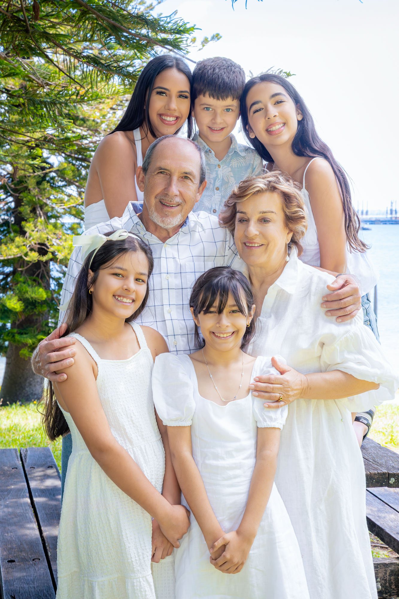 A multi-generational family portrait with grandparents, parents and children photographed outdoors by Southern Exposure Photography.