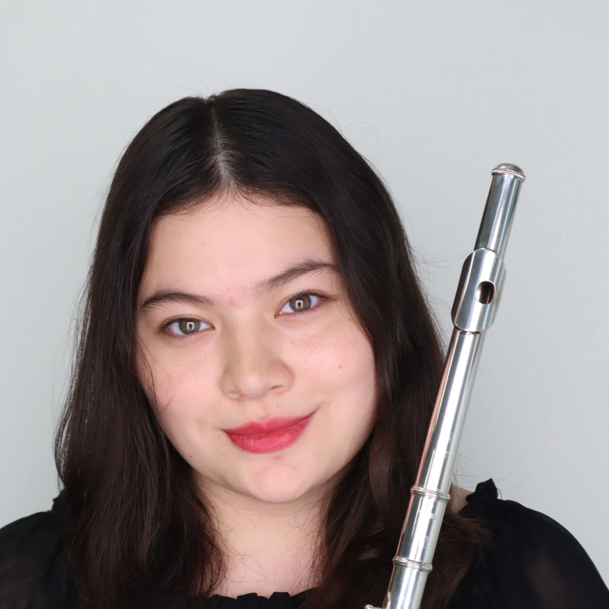 A woman with dark hair holding a silver flute, smiling, against a plain white background.