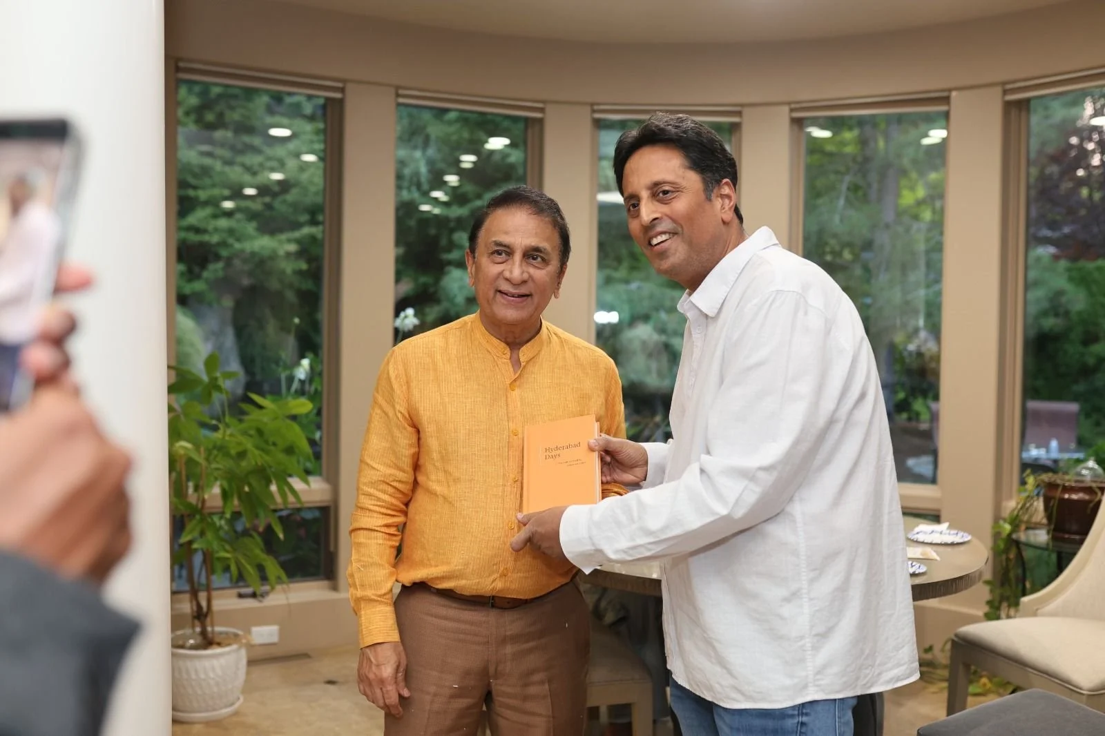Ravi presenting a copy of Hyderabad Days to Sunil Gavaskar during their meeting.