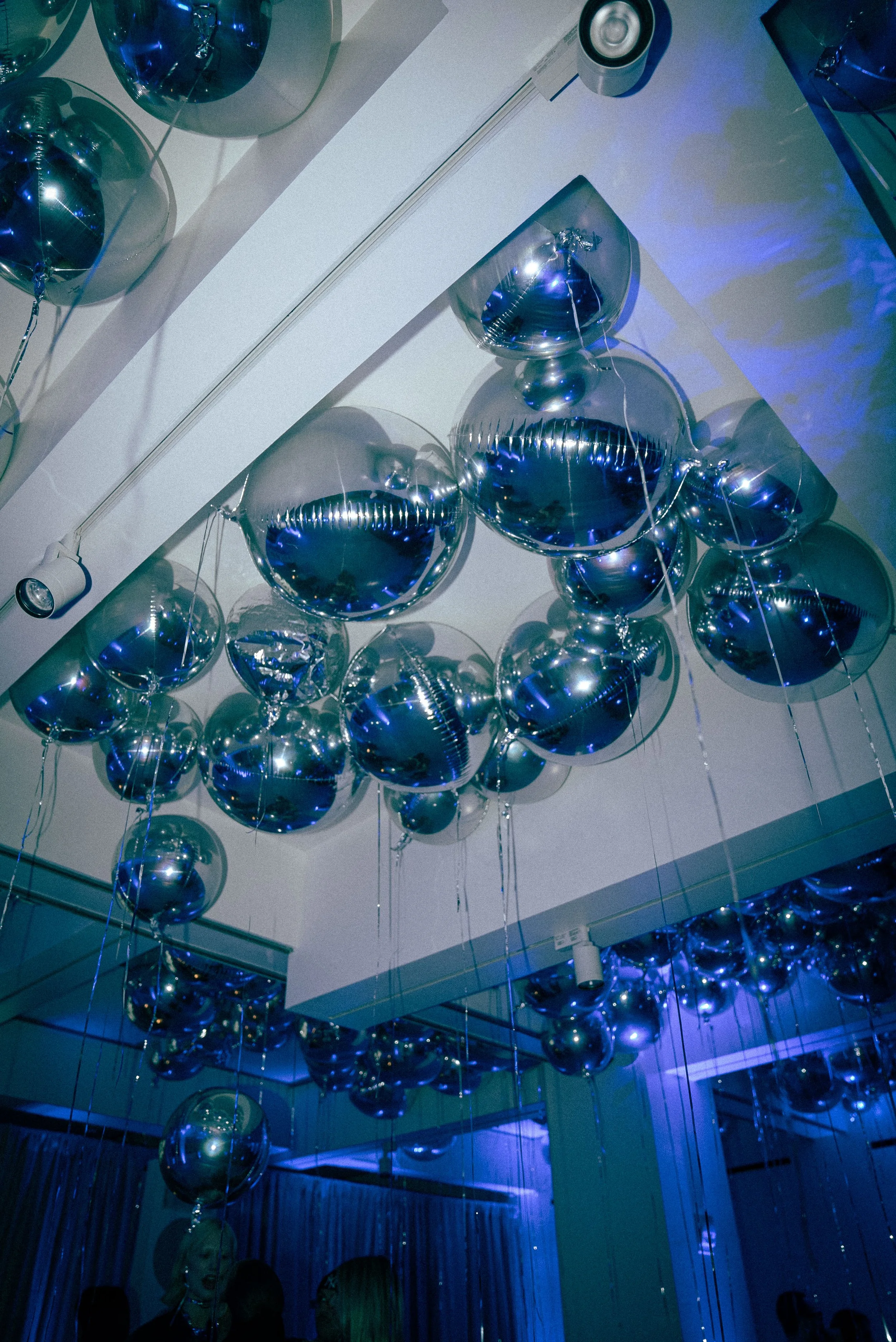 A ceiling decorated with numerous shiny silver balloons, some of which are transparent, creating a reflective and festive atmosphere.