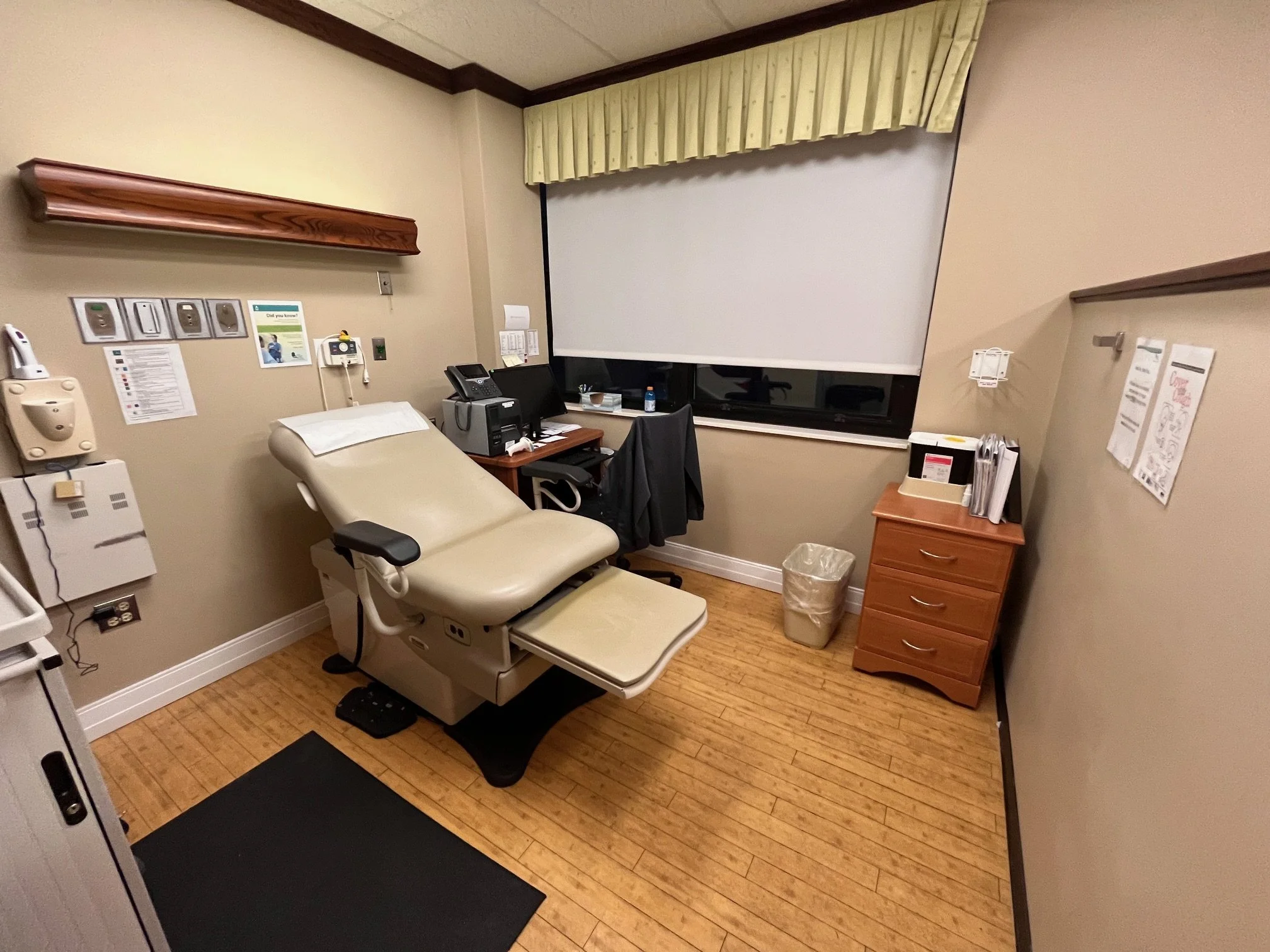 Medical examination room with an exam table, computer, and medical equipment in a hospital or clinic.