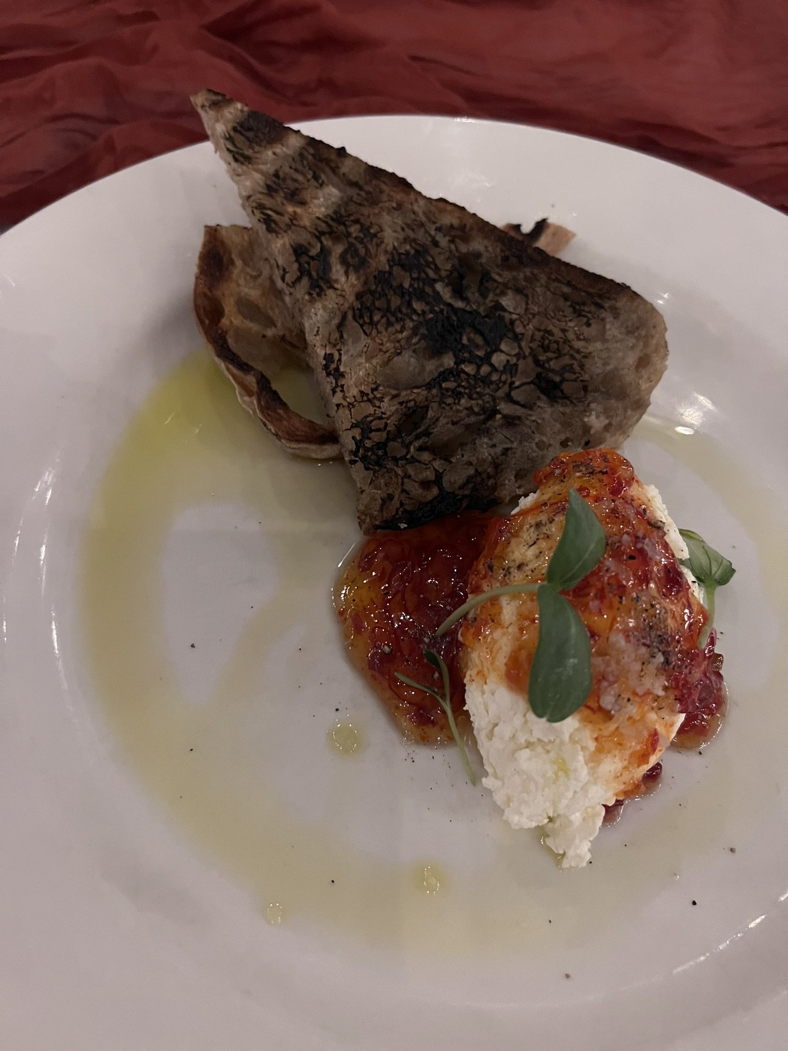 A plate of grilled fish fillet topped with tomato sauce and garnished with fresh herbs on a white plate.