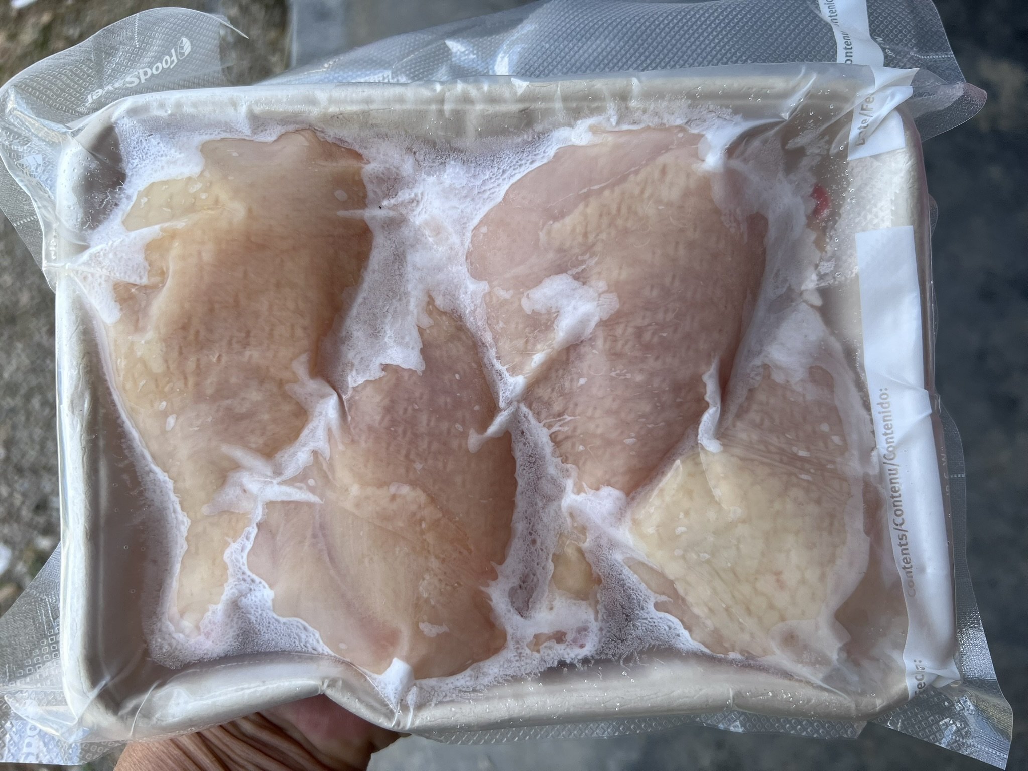 Raw chicken breasts in vacuum-sealed plastic packaging.