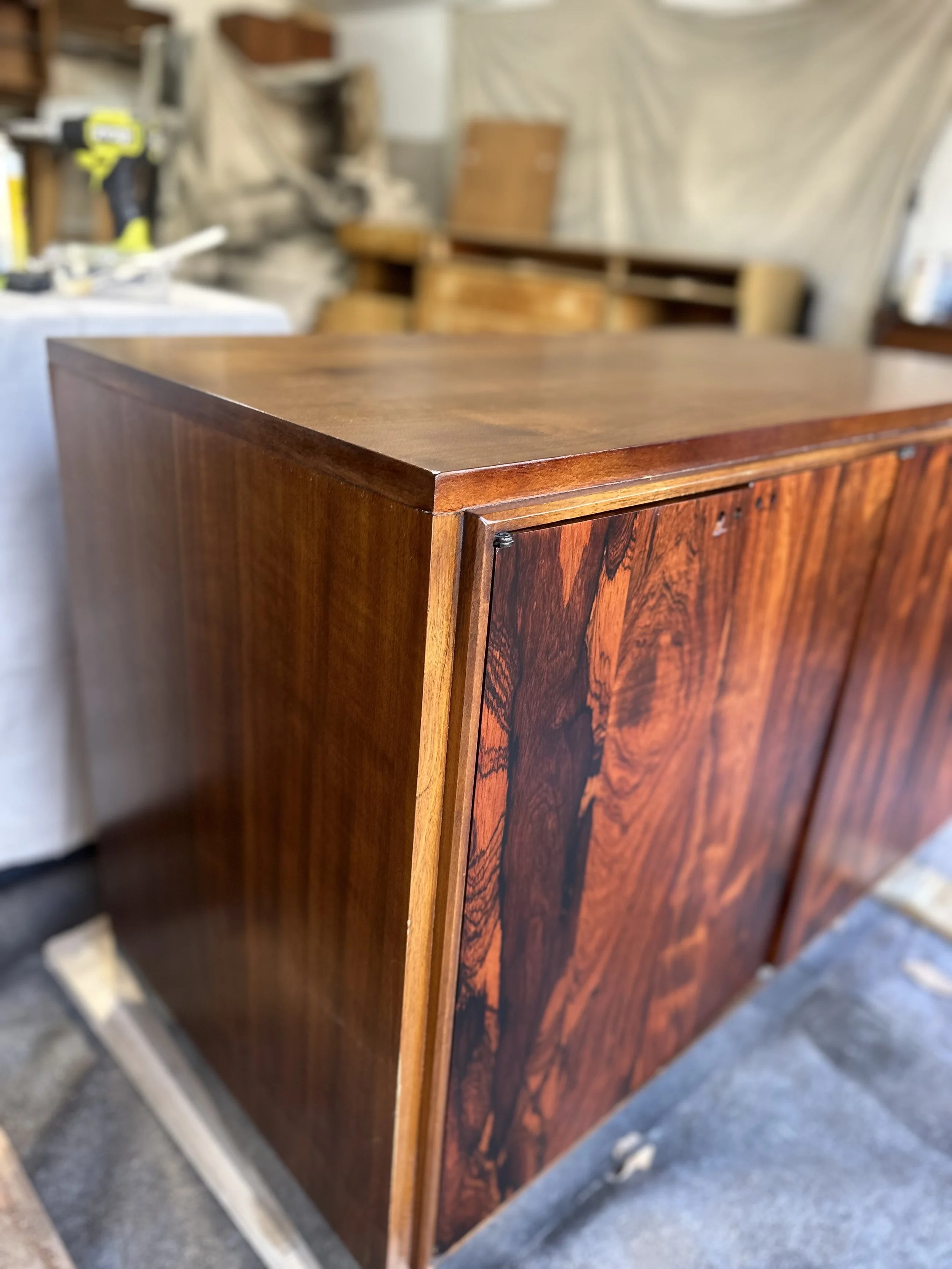 Close-up of a wooden cabinet with a polished, reddish-brown finish in a workshop.