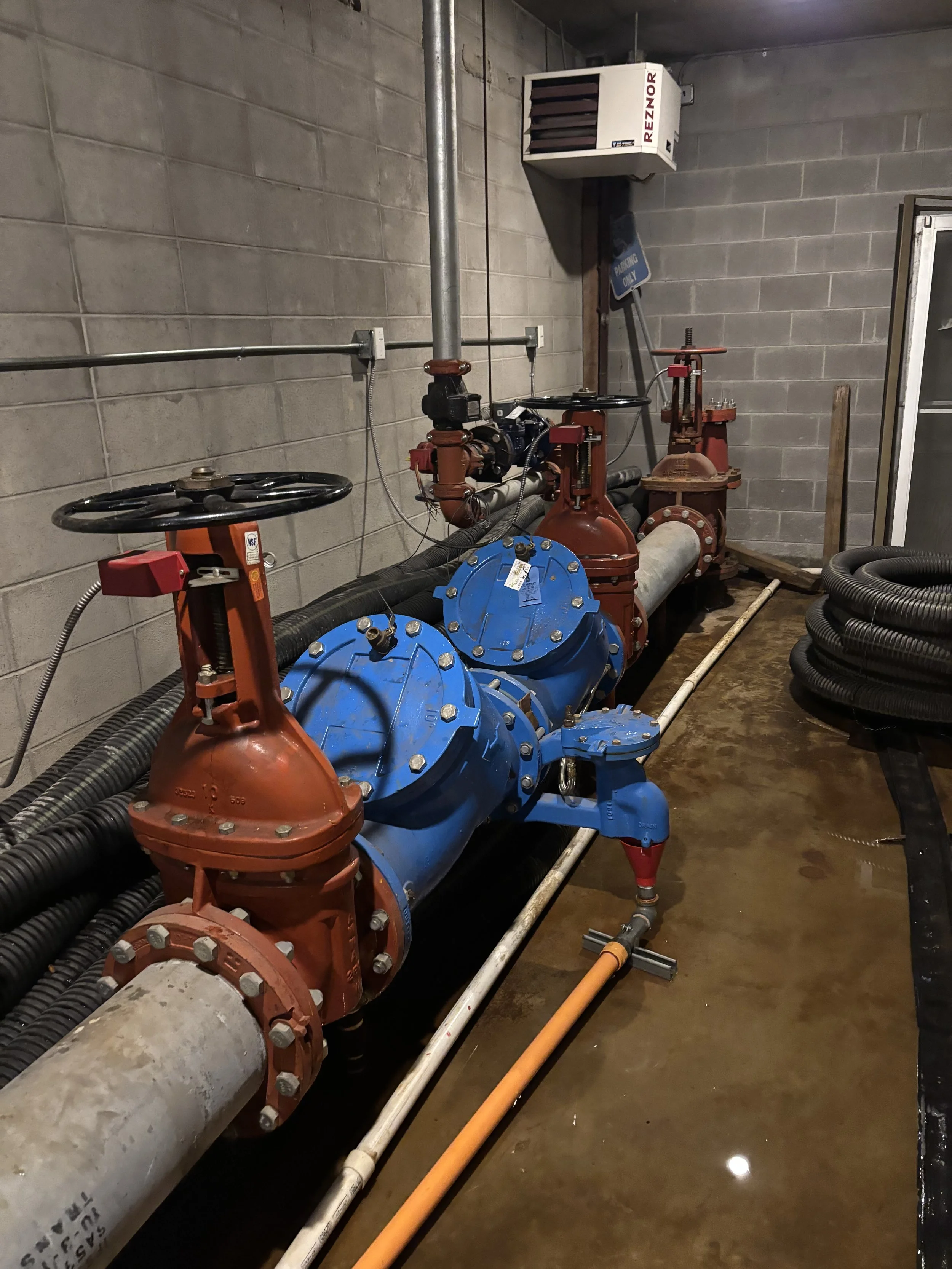 A large industrial piping system with valves and pumps in a concrete room.