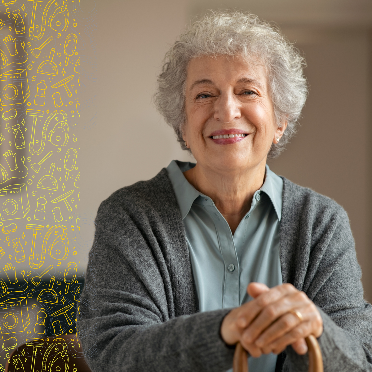 An elderly woman with gray curly hair smiling with her hands clasped in front of her, wearing a light blue blouse and gray cardigan, sitting indoors.
