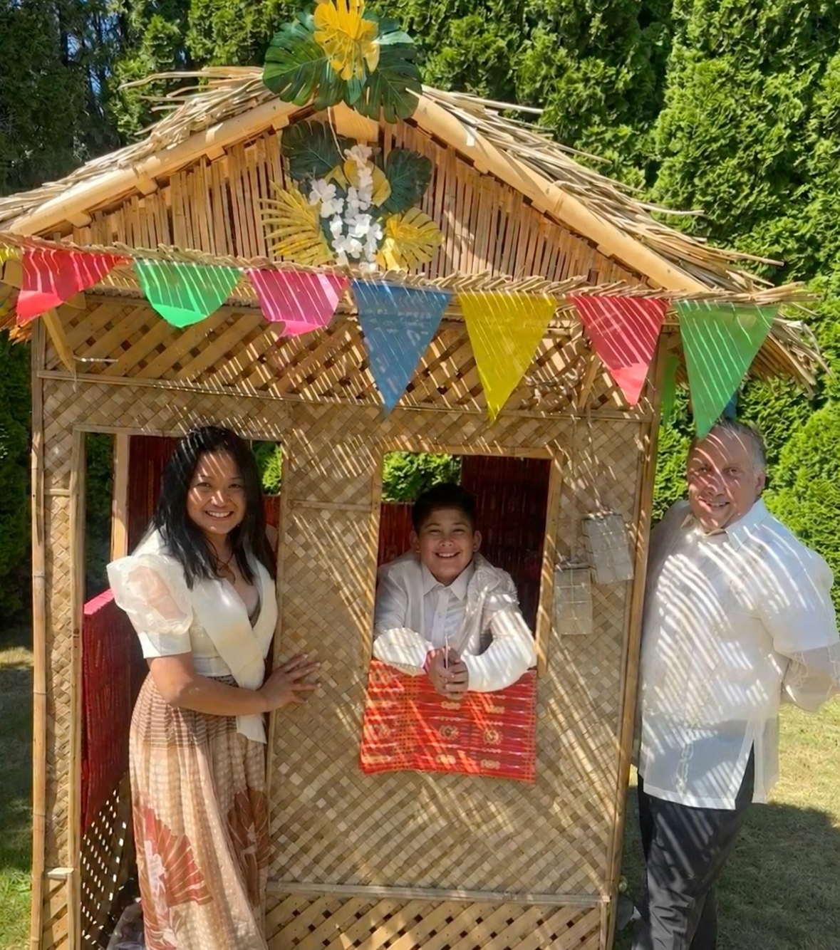 Filipino American family together beside a traditional bahay kubo