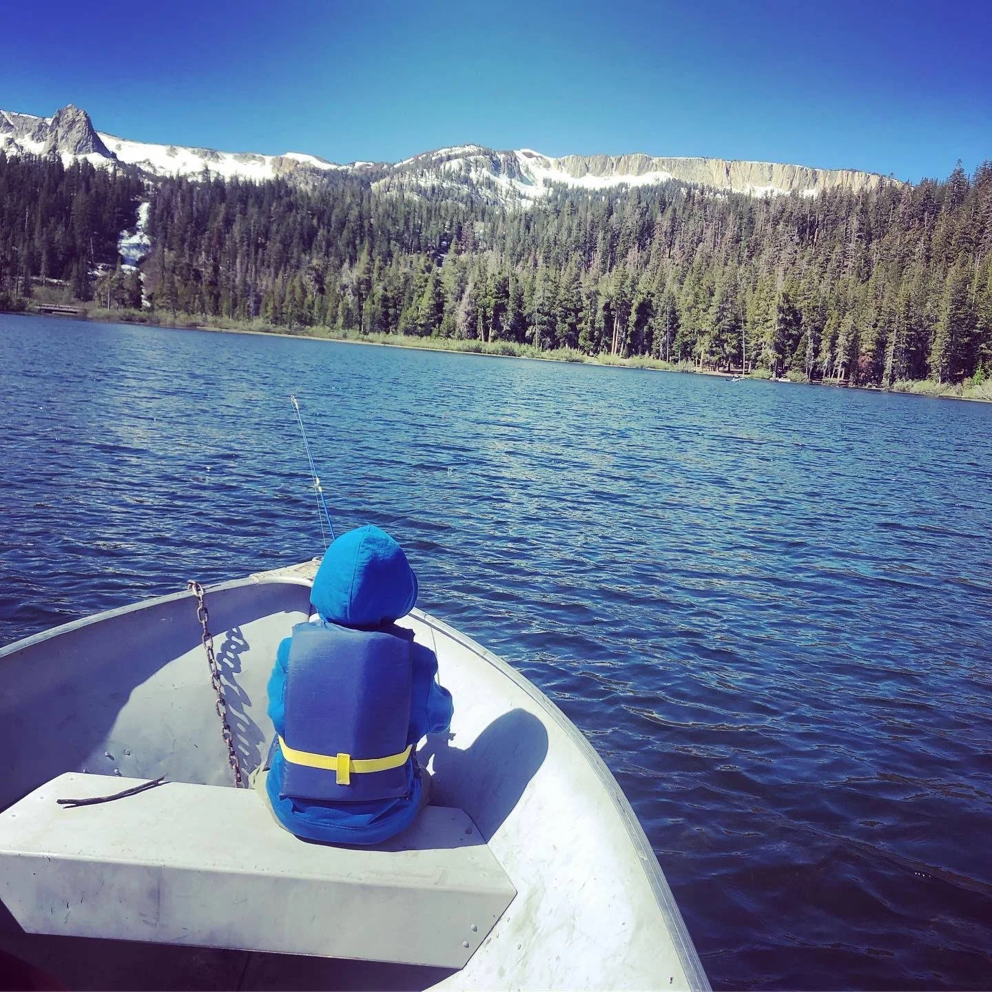 Child gazing across a mountain lake from a small boat, symbolizing movement toward healing and change.