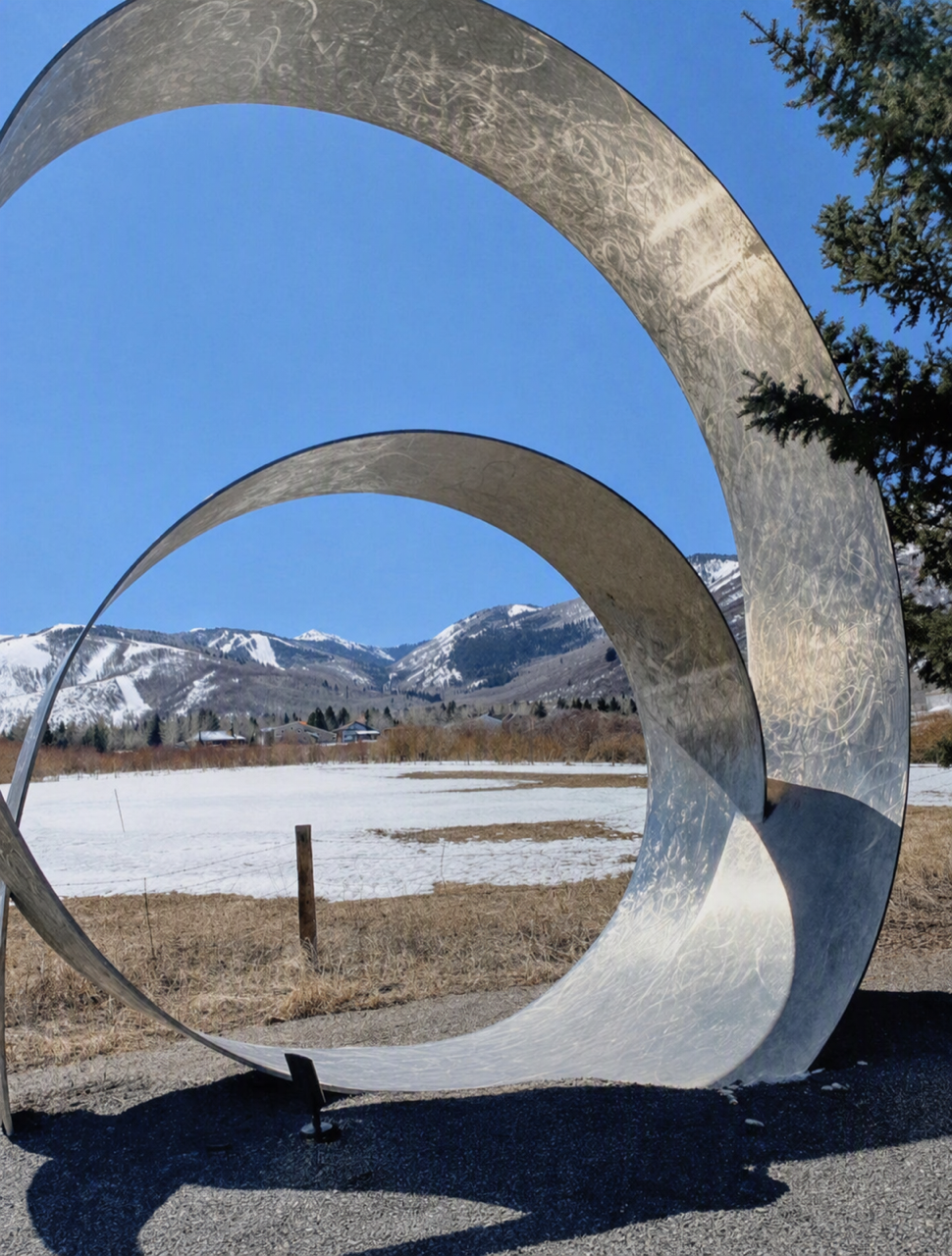 Outdoor sculpture framing snow-covered mountains in Park City, Utah.