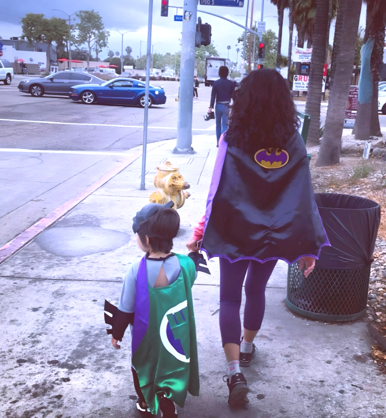 Adult and child wearing superhero capes walking together, symbolizing personal growth, resilience, and healing.