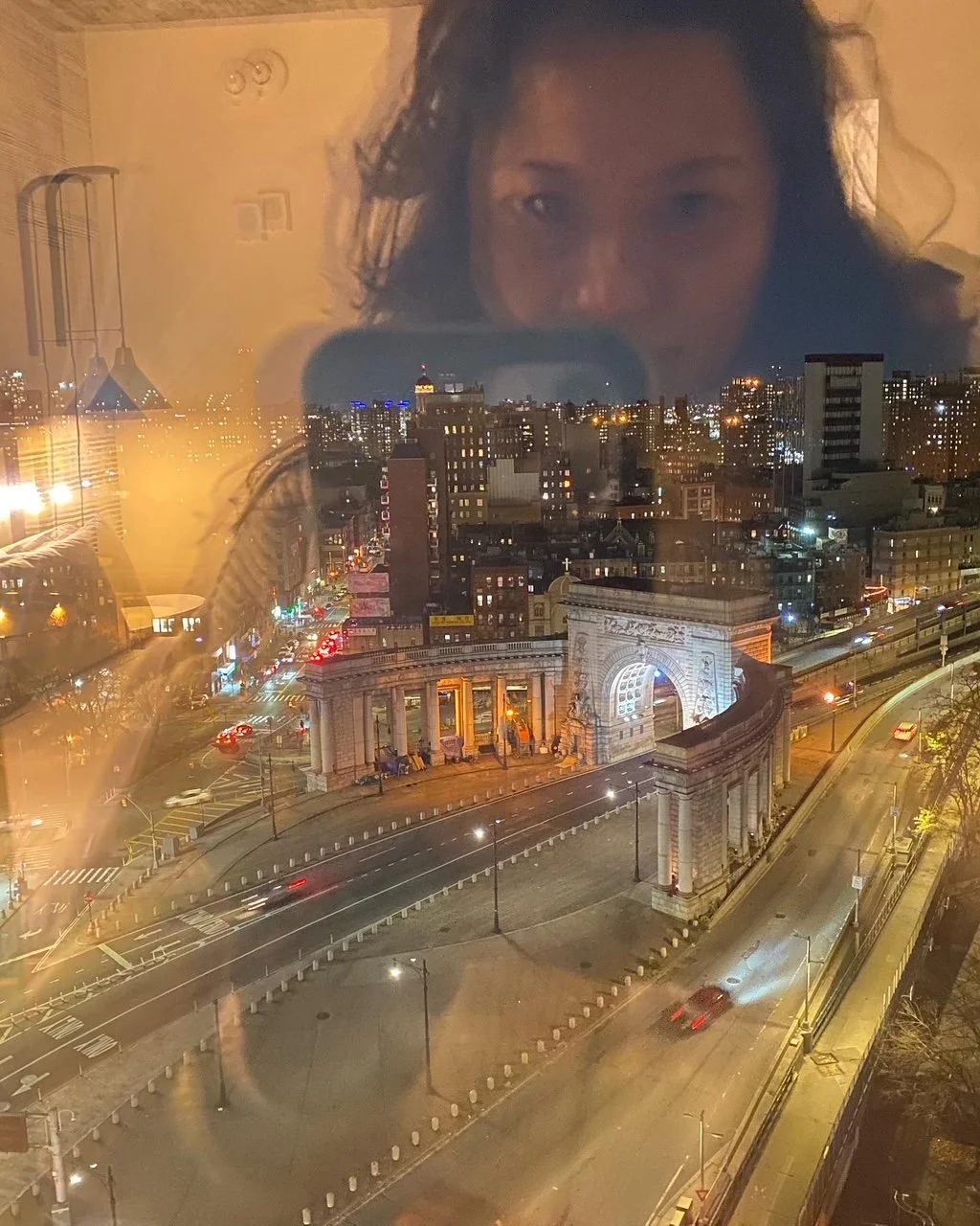 Reflection of a person overlooking a city at night