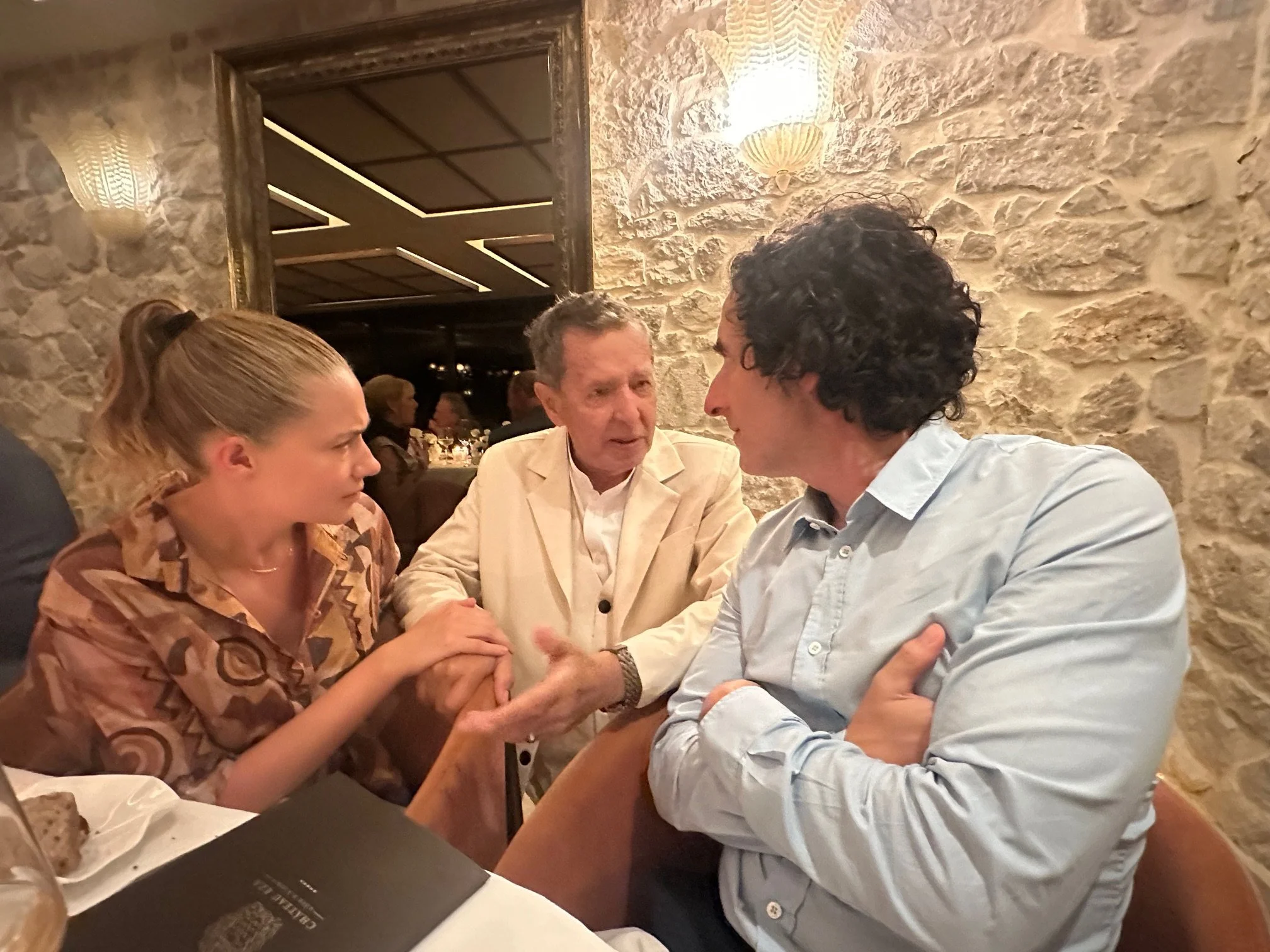 Three people engaged in conversation around a table, reflecting collaboration, trust, and shared understanding.