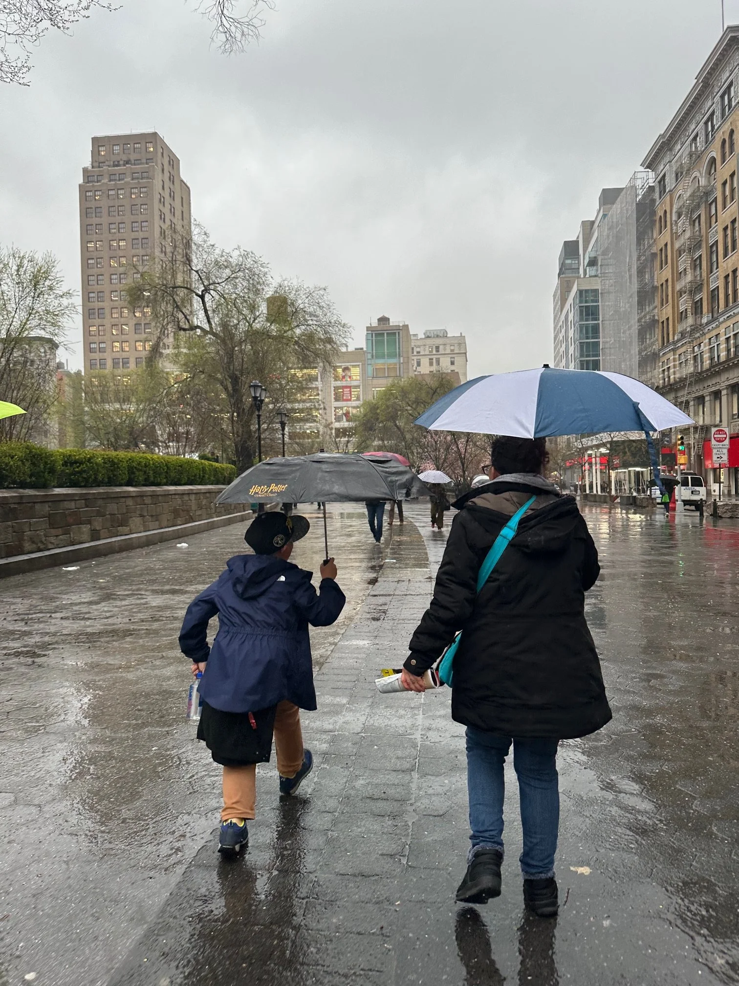 Two figures walking in rain representing the weight of unprocessed trauma addressed in therapy with Rosalie Maduro LMFT ACMHC in Los Angeles, San Francisco, Park City