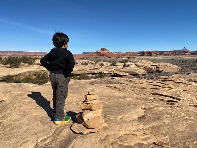 Child looking across a desert landscape toward distant rock formations