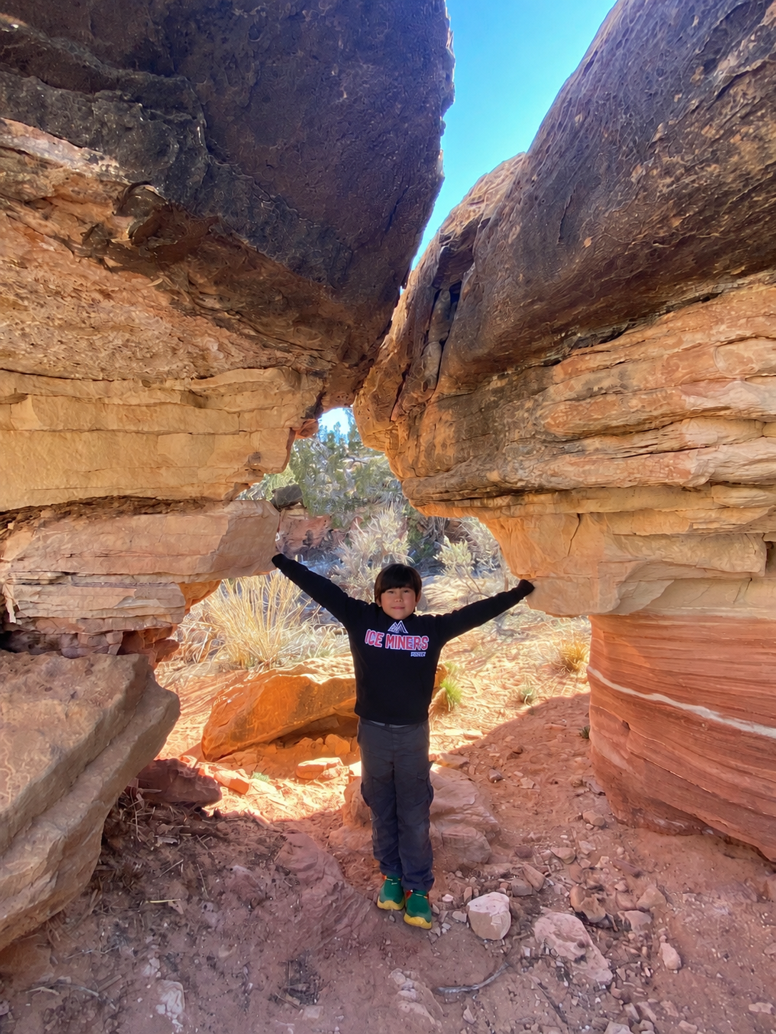 Person standing beneath a large red rock formation