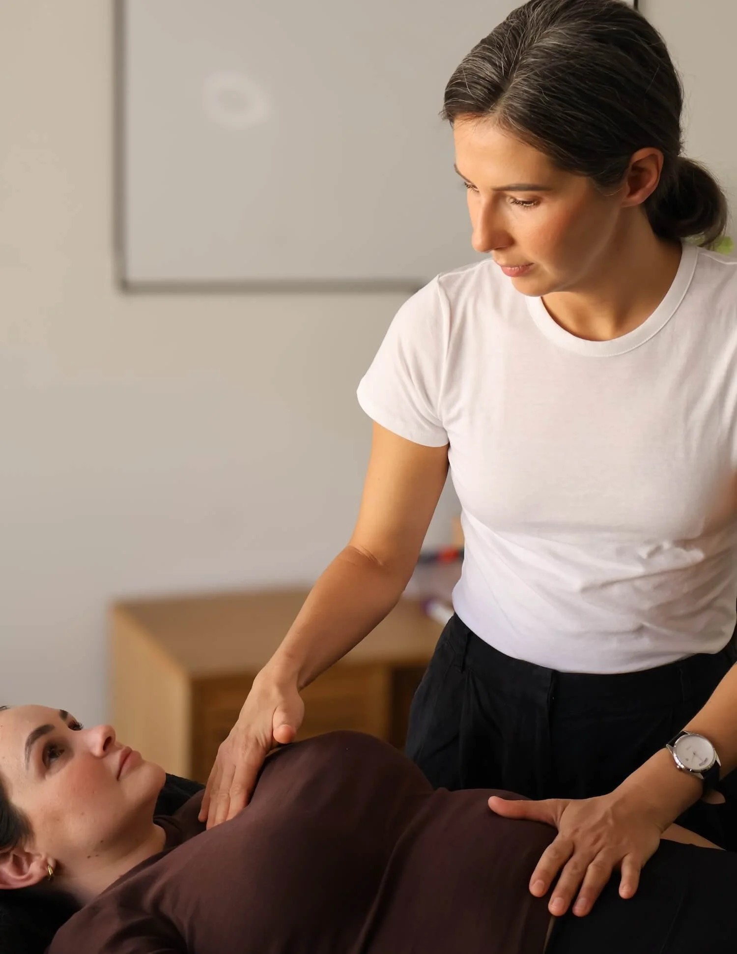 A woman performing chiropractic adjustment on another woman lying on a table.