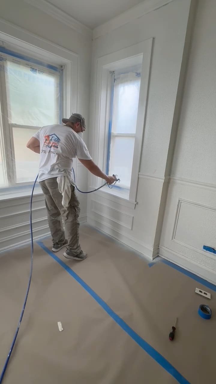Professional painter spraying interior window trim and walls in a Chicago home