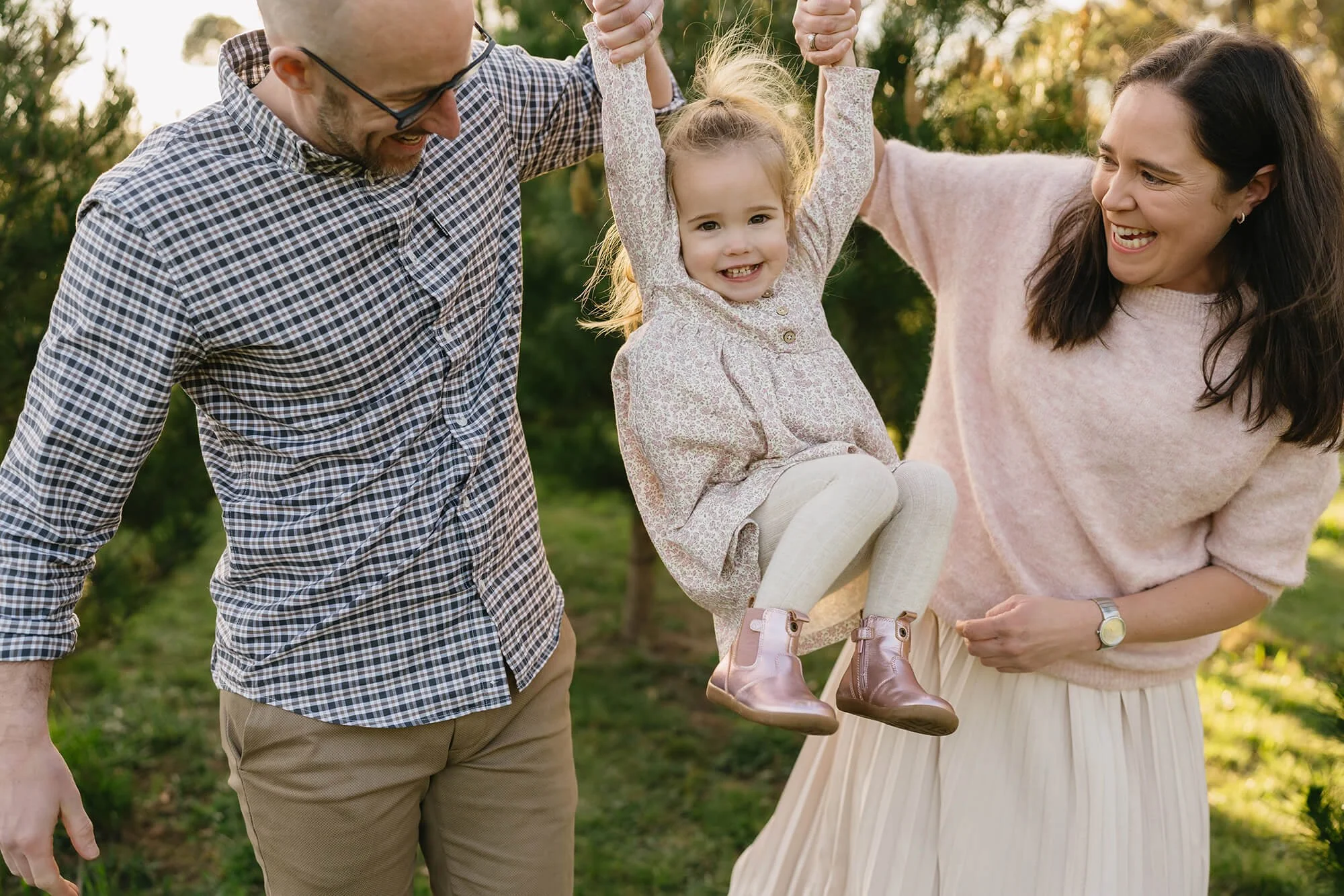 Family cuddling amongst Christmas trees during an outdoor Christmas mini session in Richmond, Tasmania