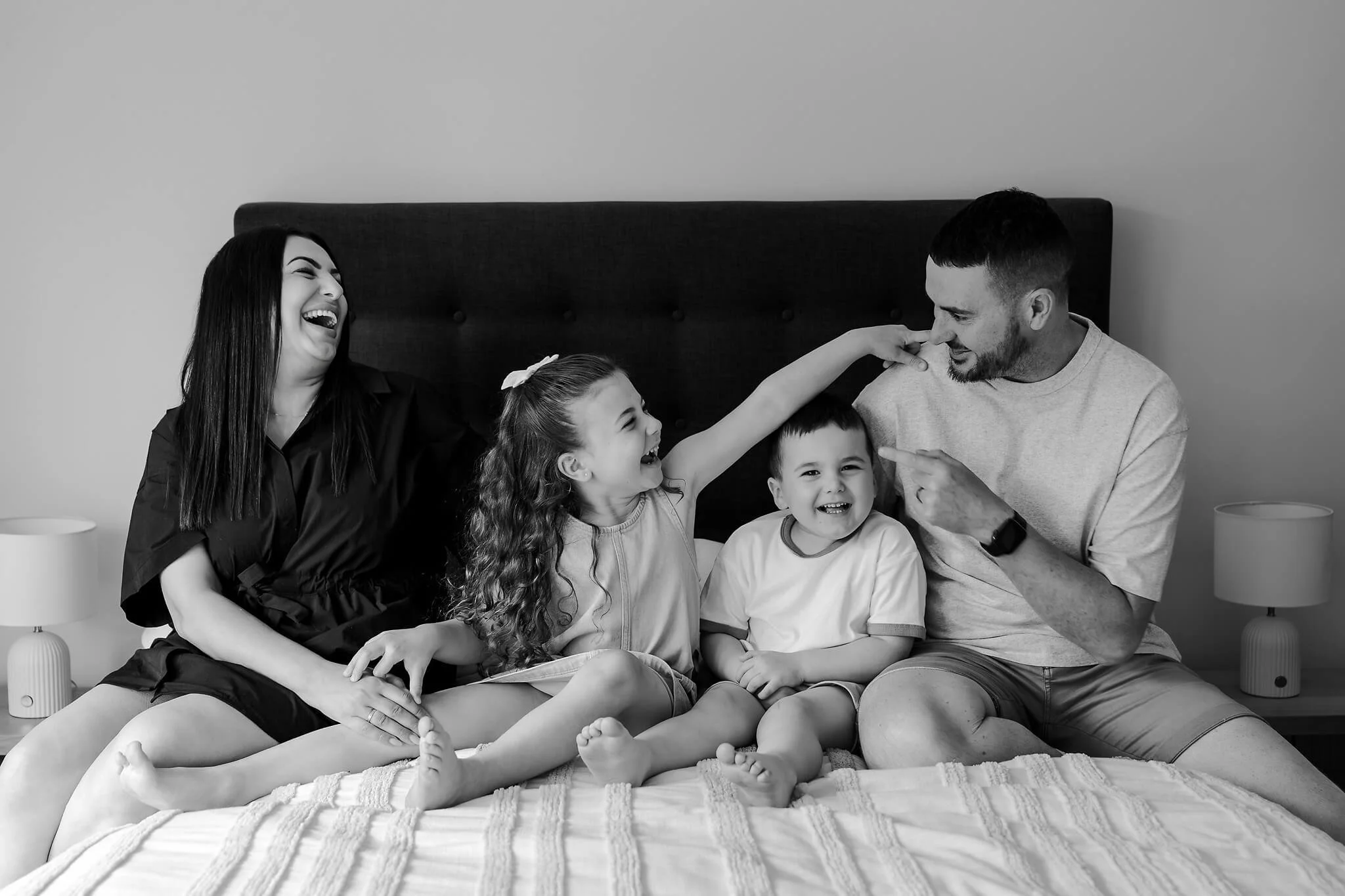 Hobart family sitting on their bed laughing together having their photo taken