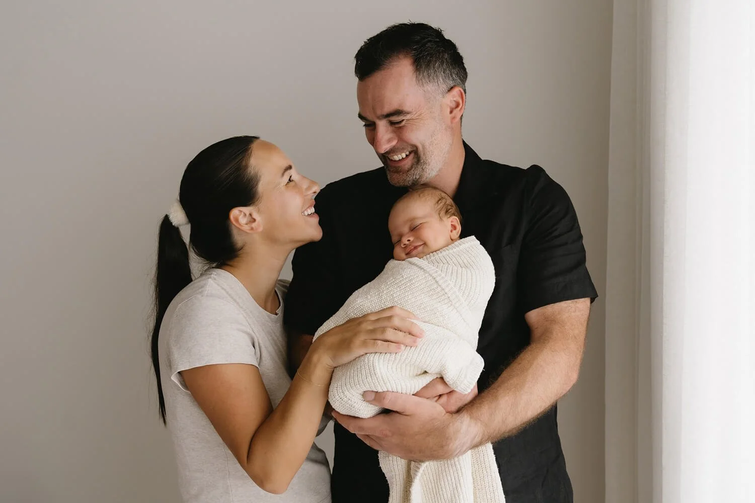 Mum and dad holding newborn baby at being photographed by Hobart Family photographer