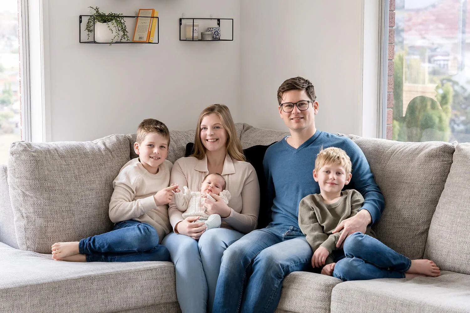 Family sitting on couch cuddling newborn baby