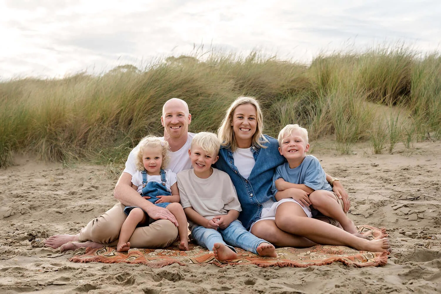 Family with three young children sitting on a blanket at the beaching at Hobart family photoshoot