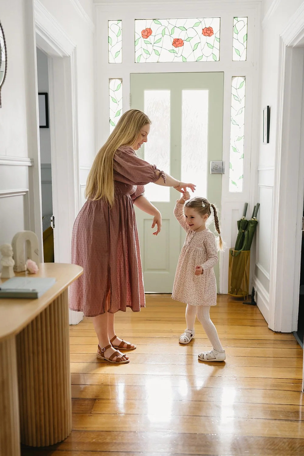 Mother twirling daughter in hallway