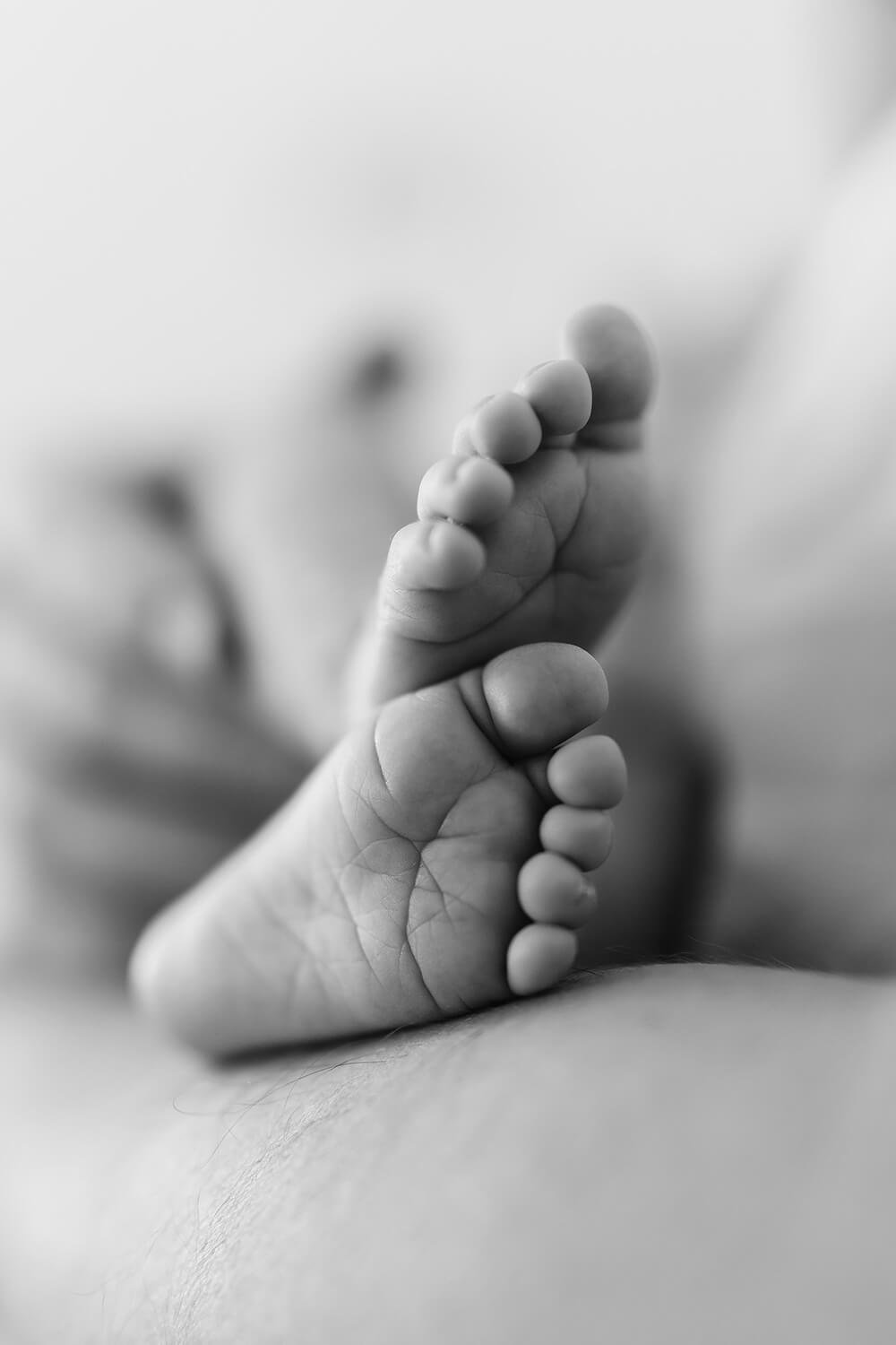 Close-up of a tiny baby's foot in black and white, emphasizing soft skin and delicate toes.