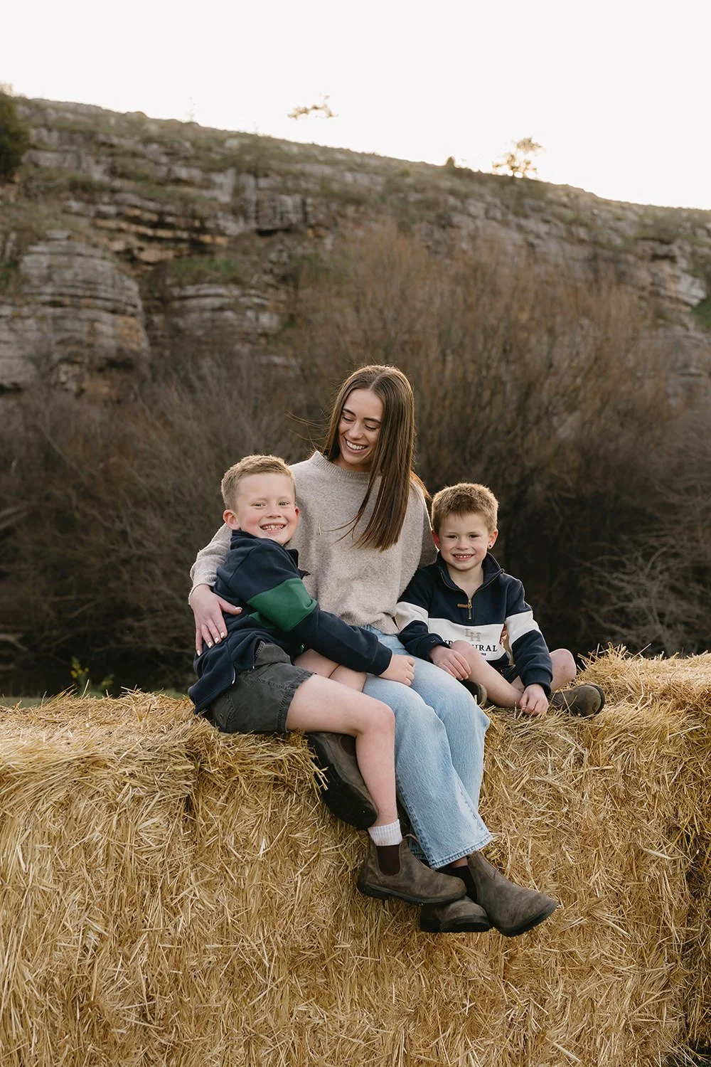Family sitting on hay bale having their photo taken by Hobart Family Photographer