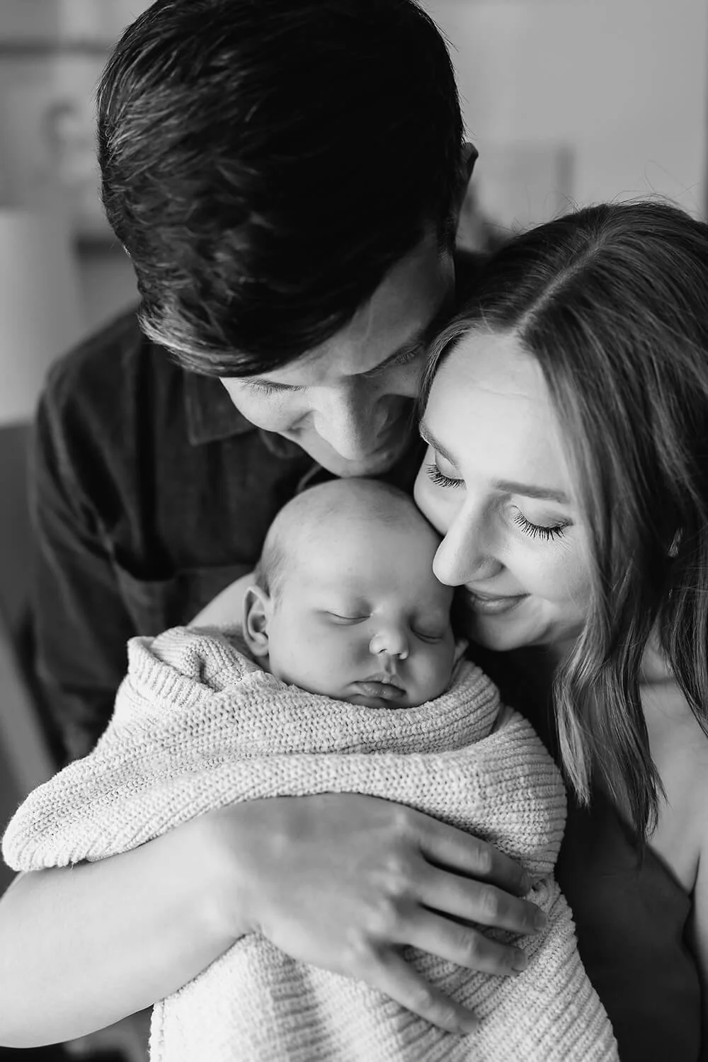 Mum and dad holding newborn baby being photographed by a Hobart photographer