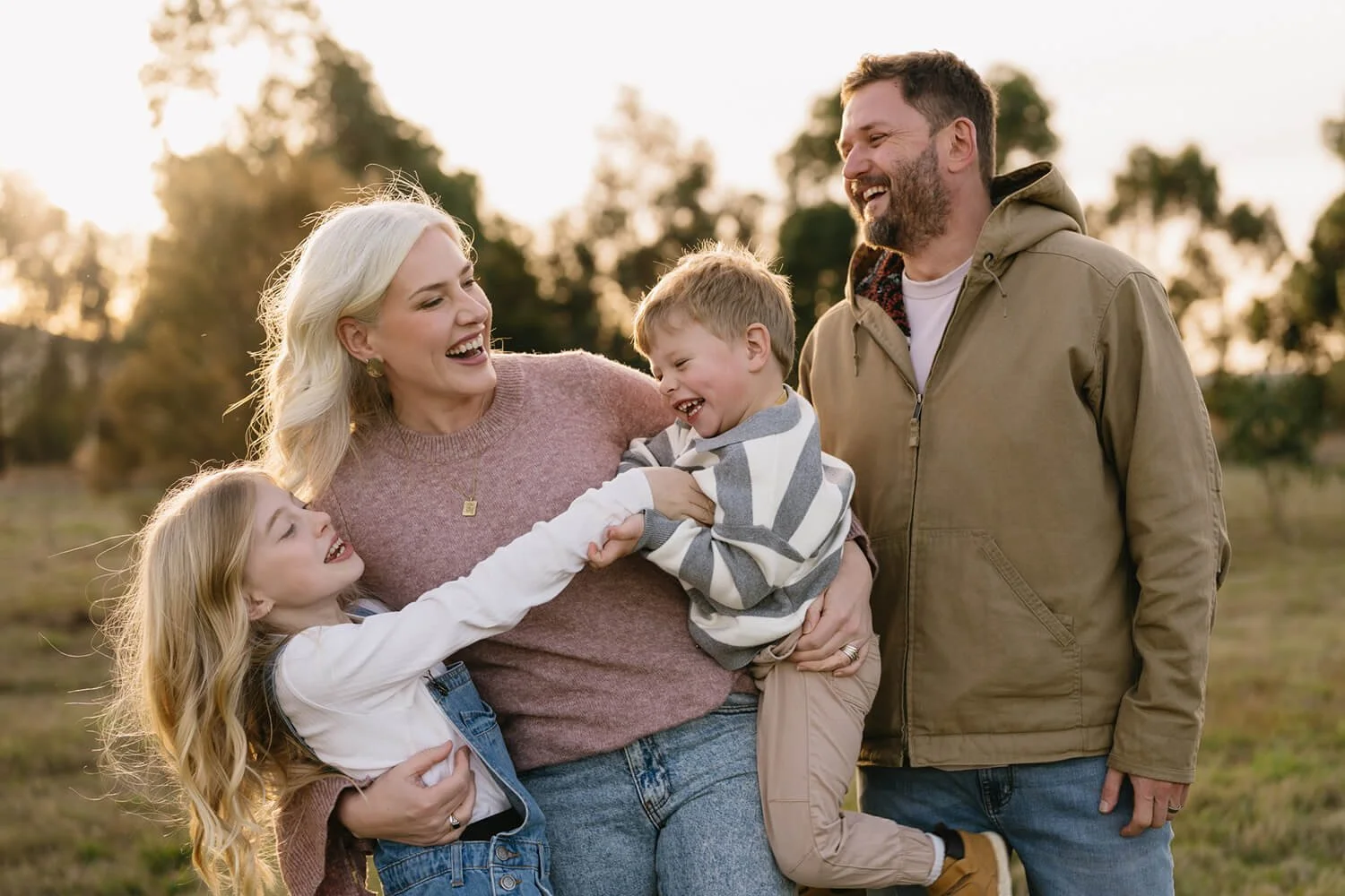 Hobart Family Photographer photographs smiling family in field