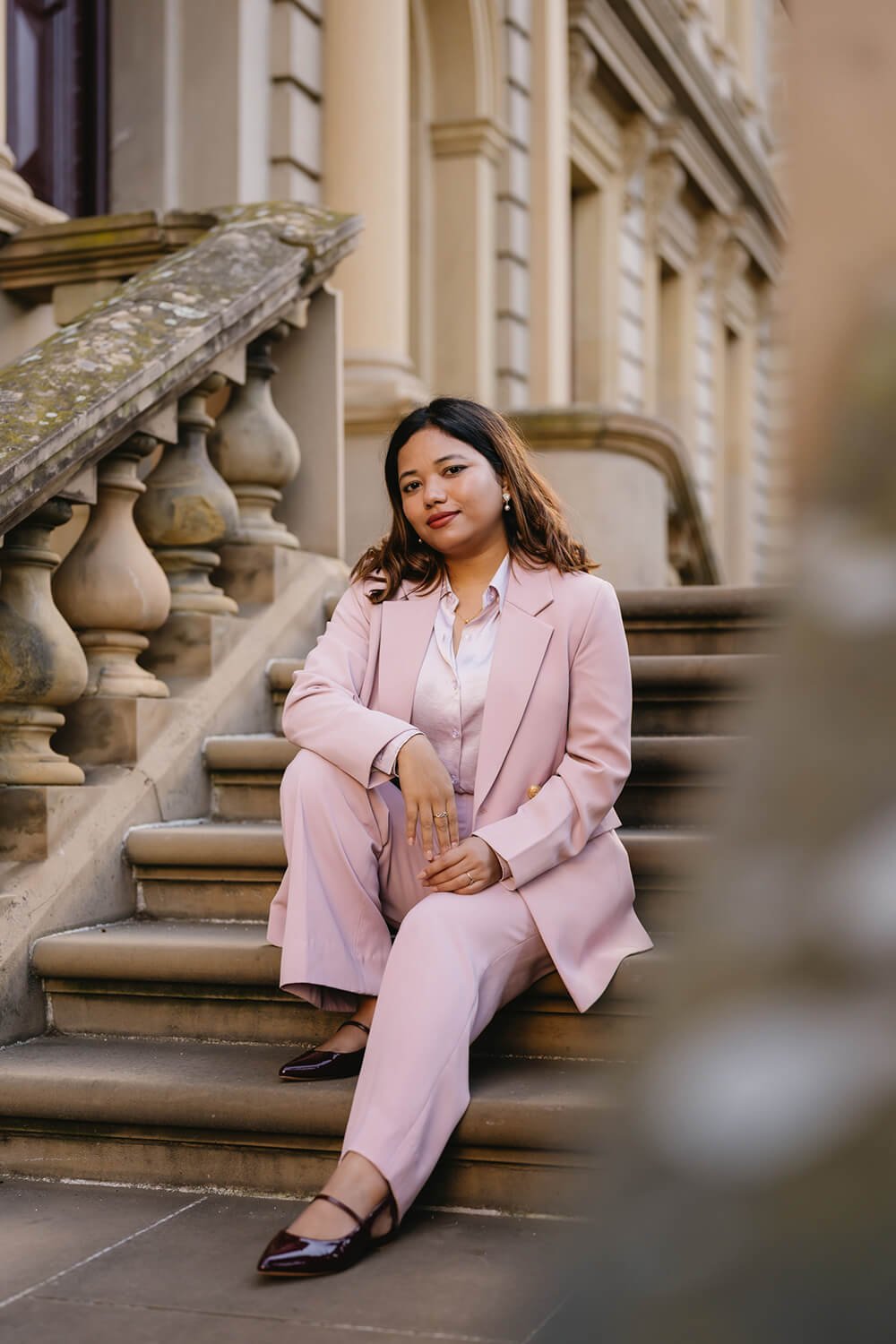 Professional woman sitting on steps of a historic Hobart building at branding photoshoot