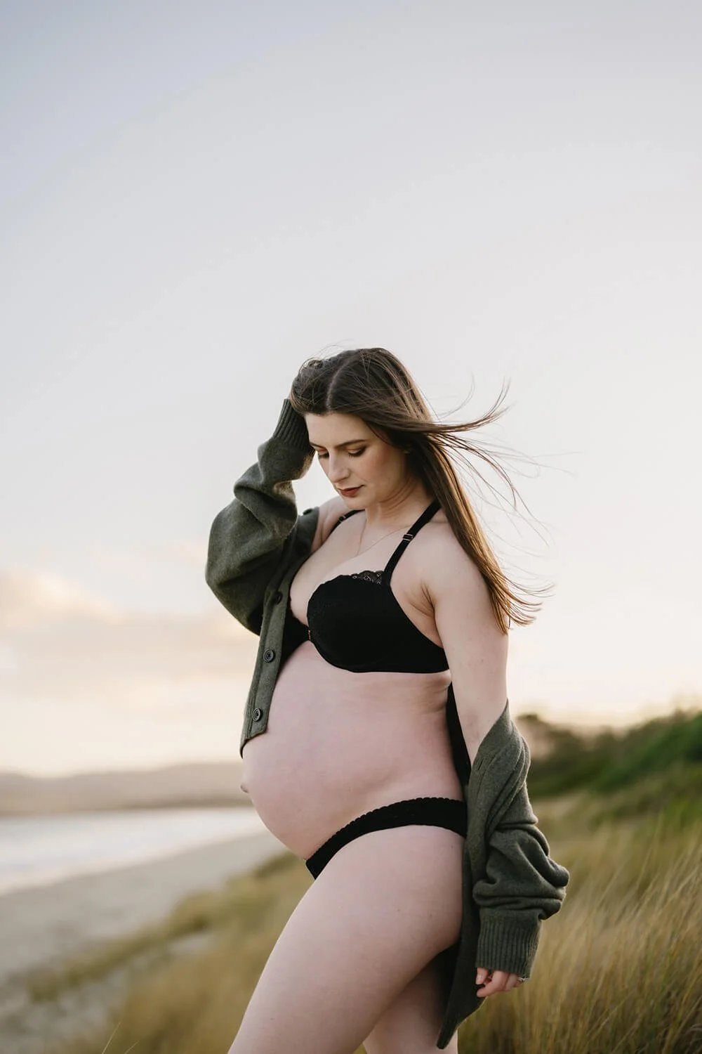 Pregnant woman in bikini on beach being photographed by Hobart maternity photographer