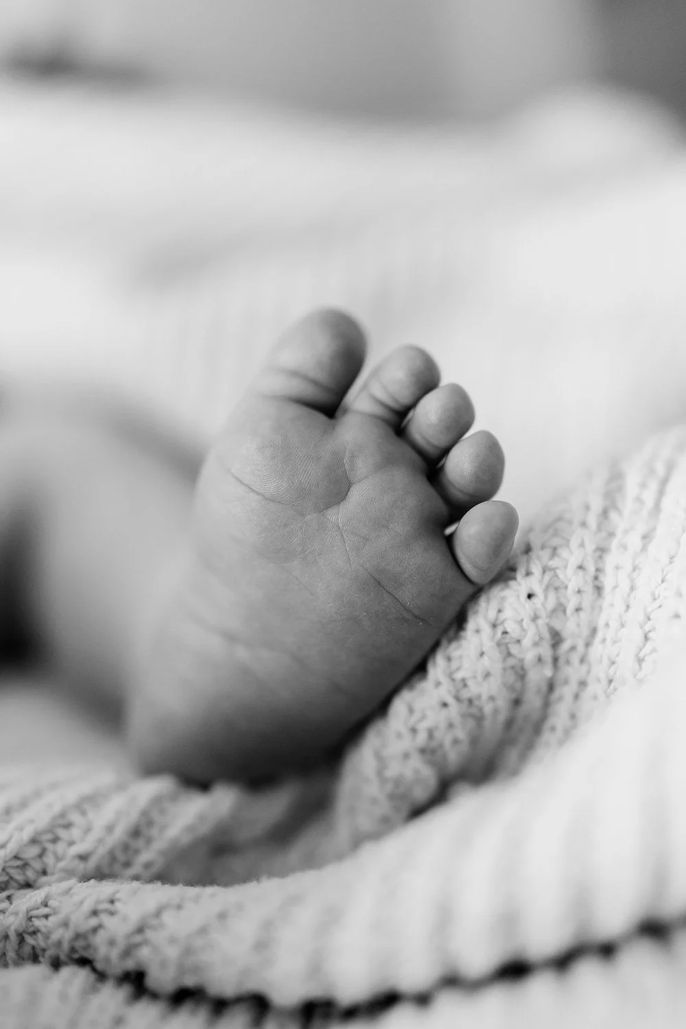 Close-up of a newborn baby's hand, resting on a soft, knitted blanket.